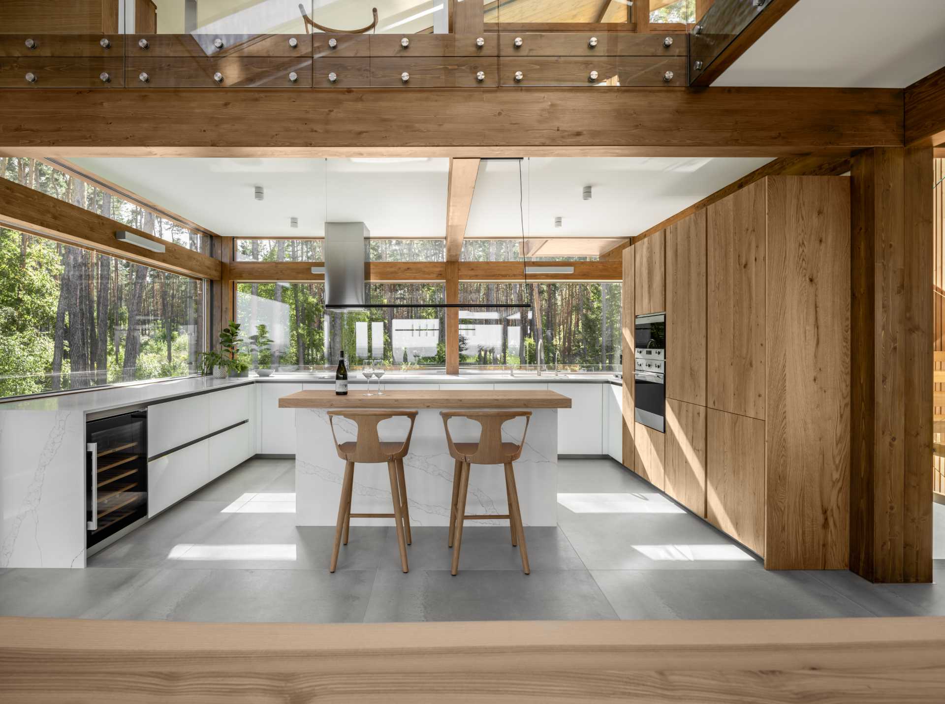 In this modern kitchen, minimalist white cabinets have been paired with wood cabinetry for a contemporary look, while windows act as a backsplash and allow the natural light to flood through to the space.