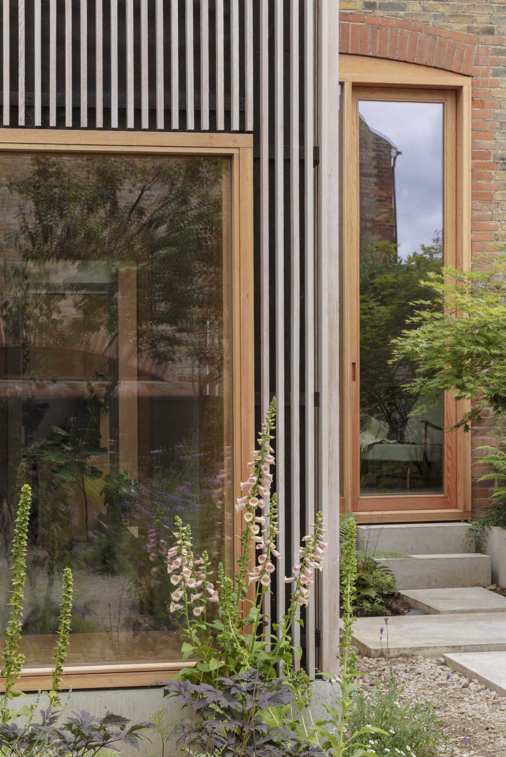 A modern home addition with large picture windows is covered in wood slats made from Douglas Fir.