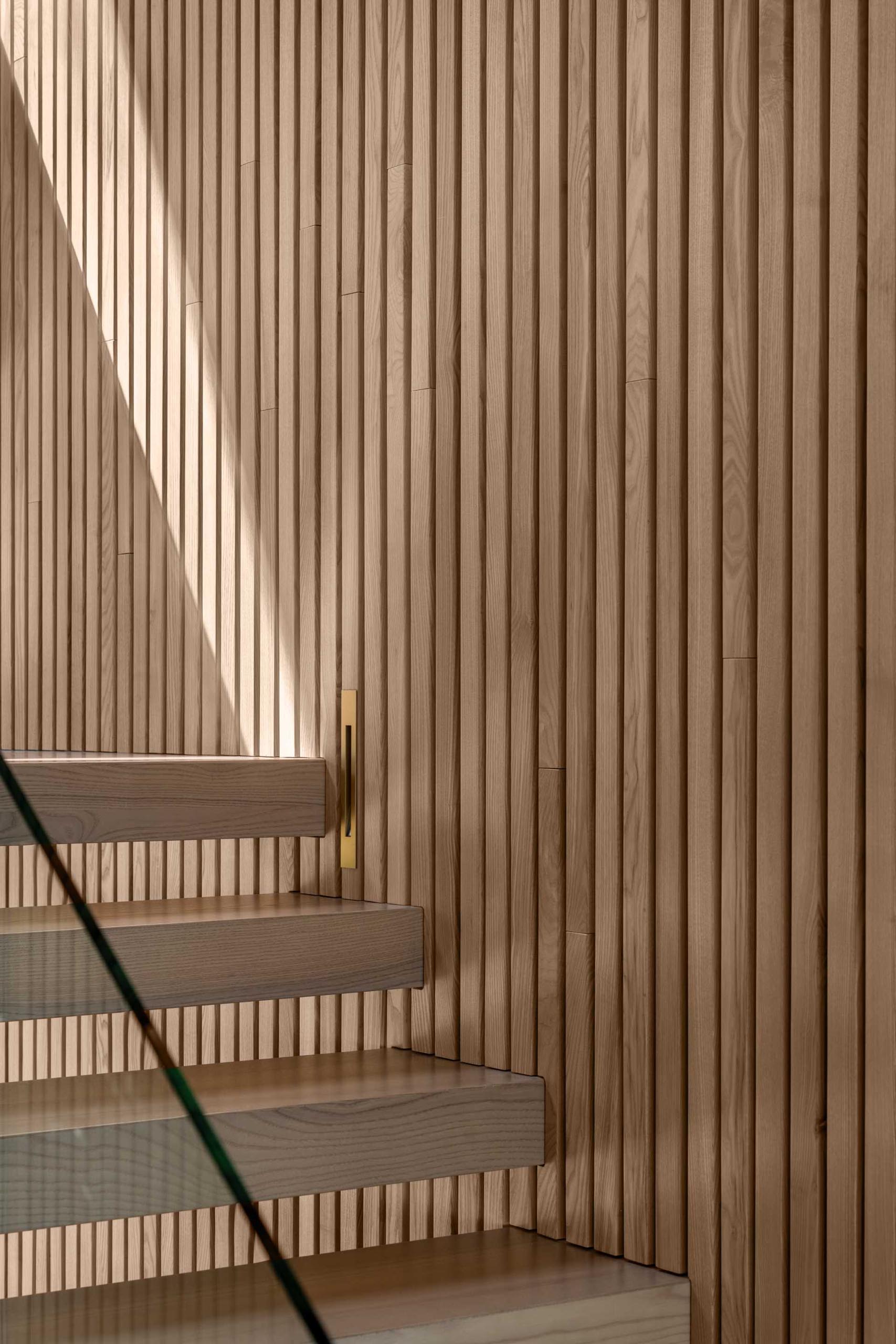 Vertical wood slats run alongside the wood stairs, while small vertical lights make it easy to travel up and down the stairs at night.