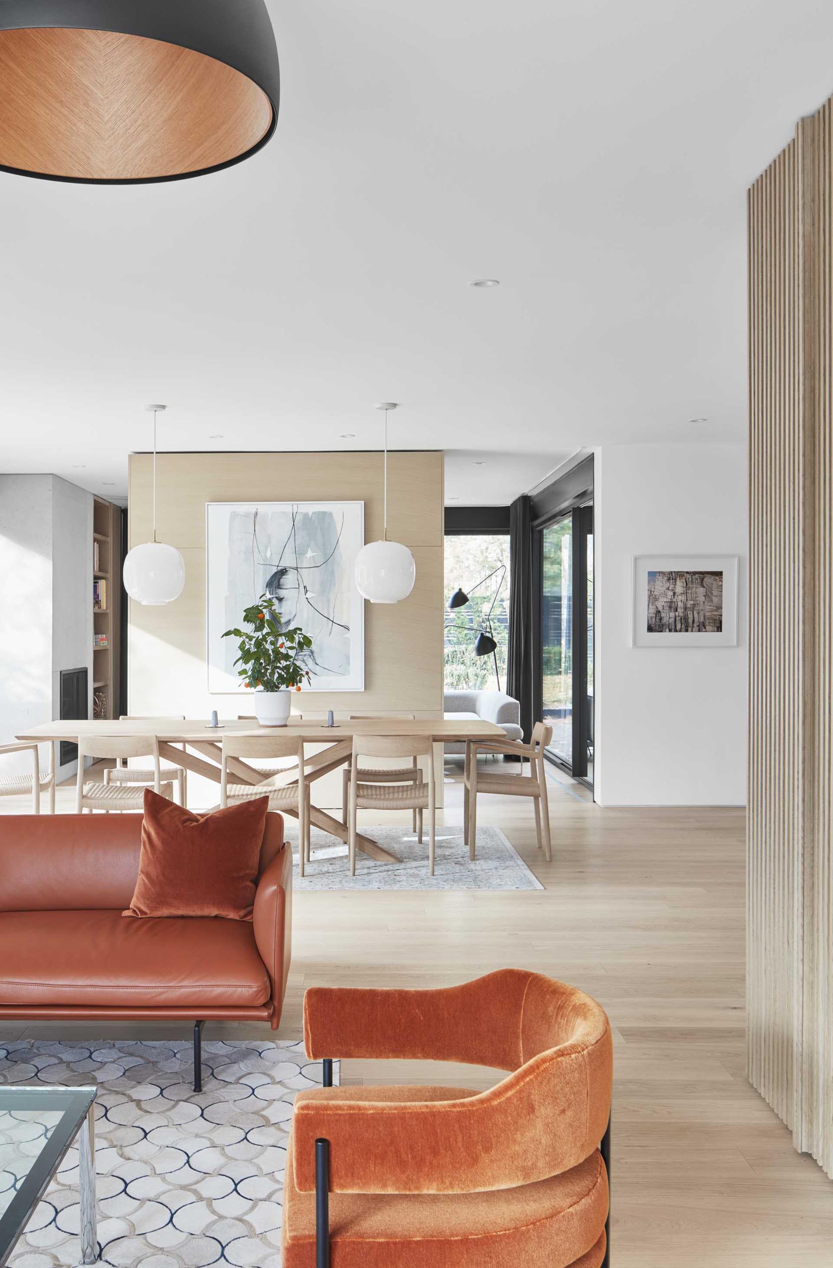 This modern dining area has a large wood table and matching chairs, two simple white pendant lights hang above the table for a contemporary look.