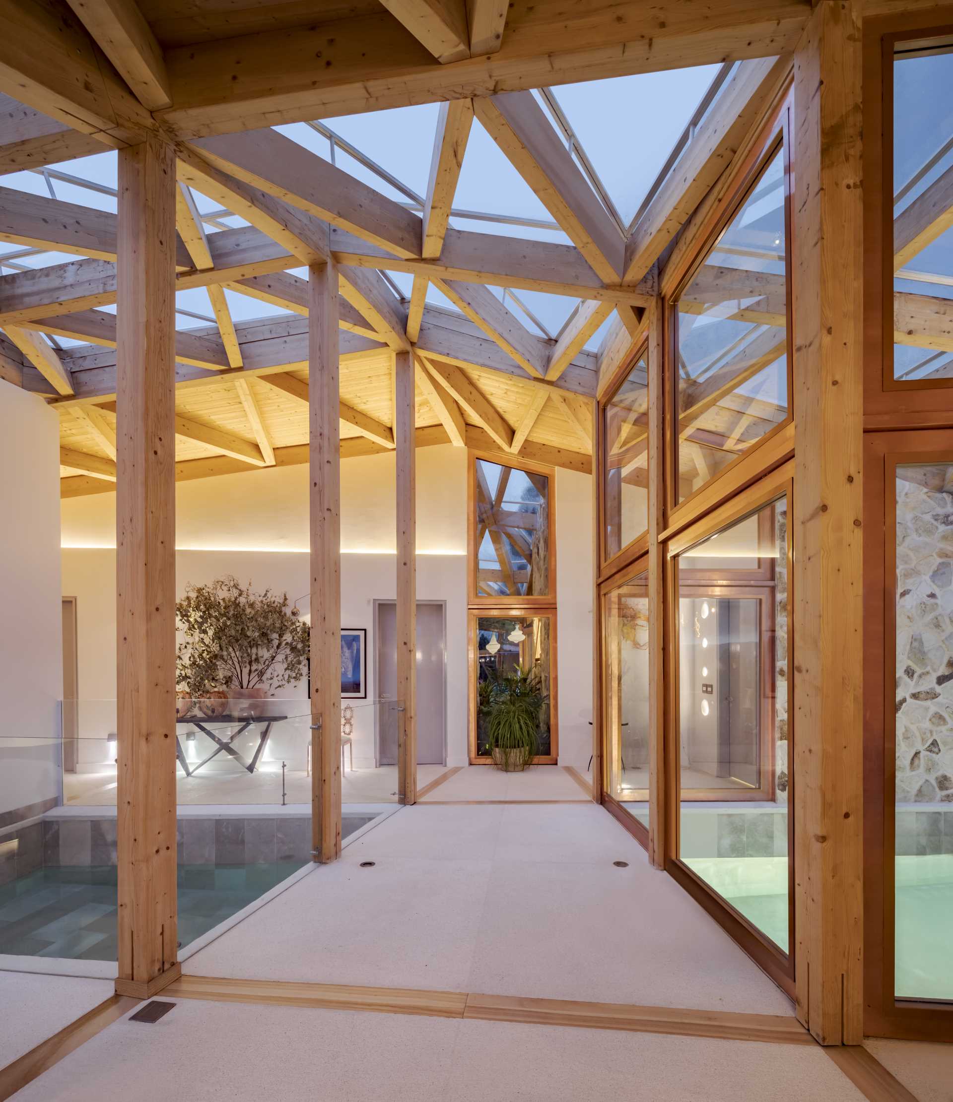 A modern home with a walkway that passes over an indoor swimming pool.