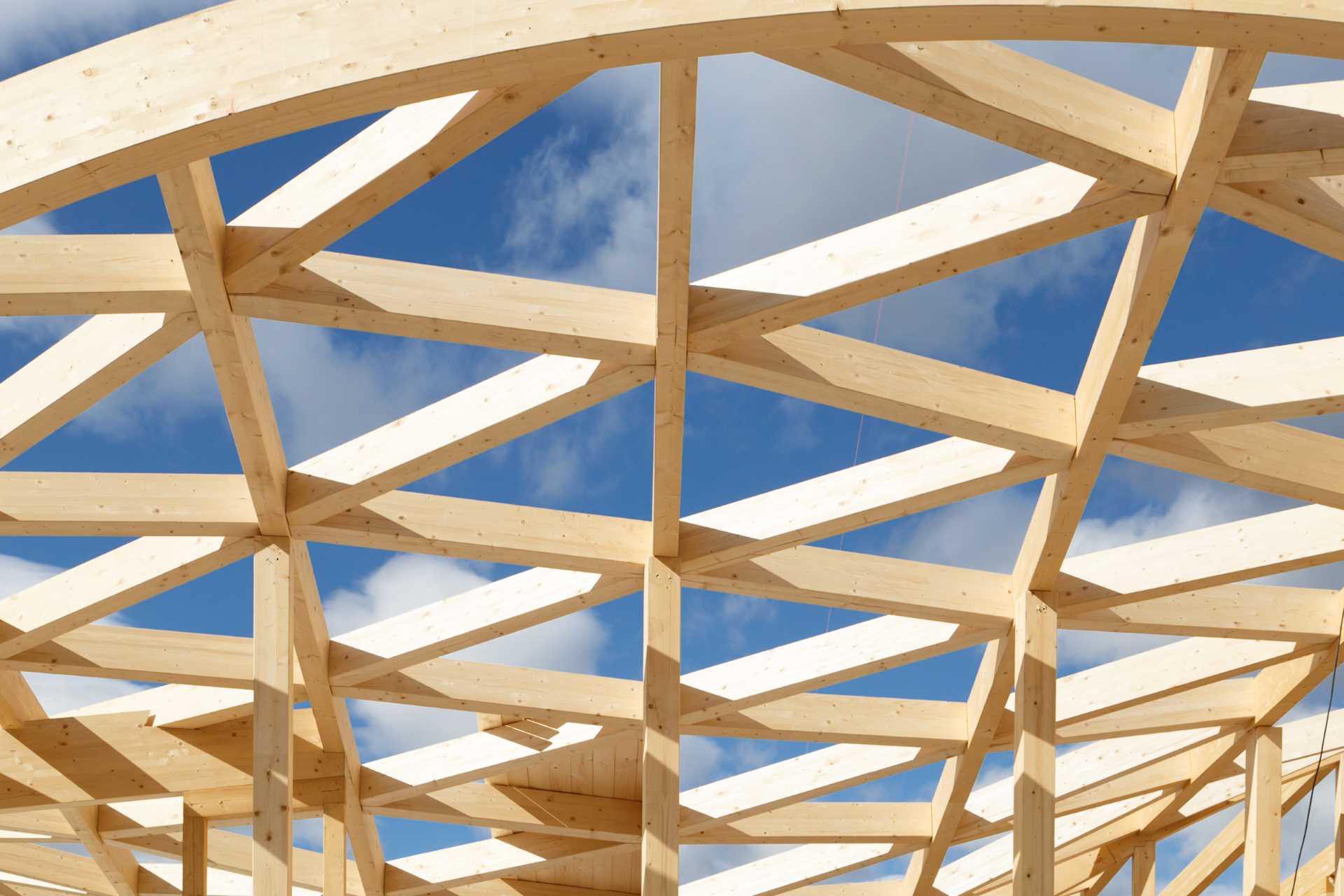 The construction of a wood house with a wavy roof.