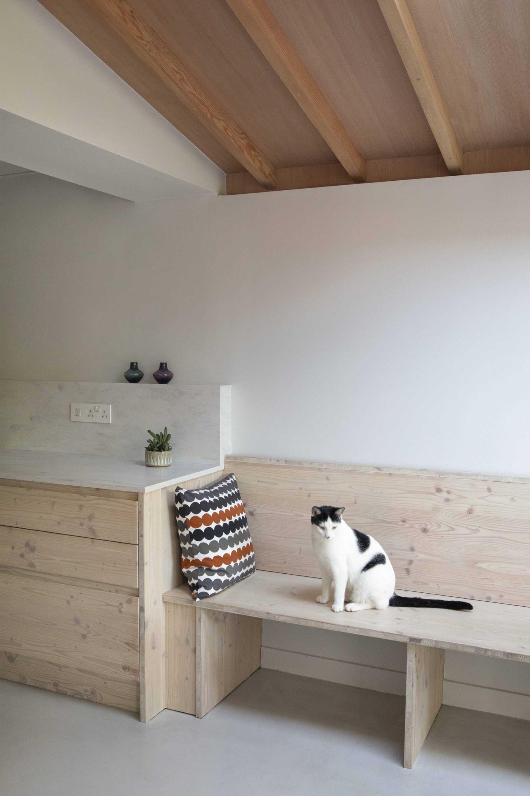 A contemporary galley kitchen with wood cabinets continues on to become a dining bench.