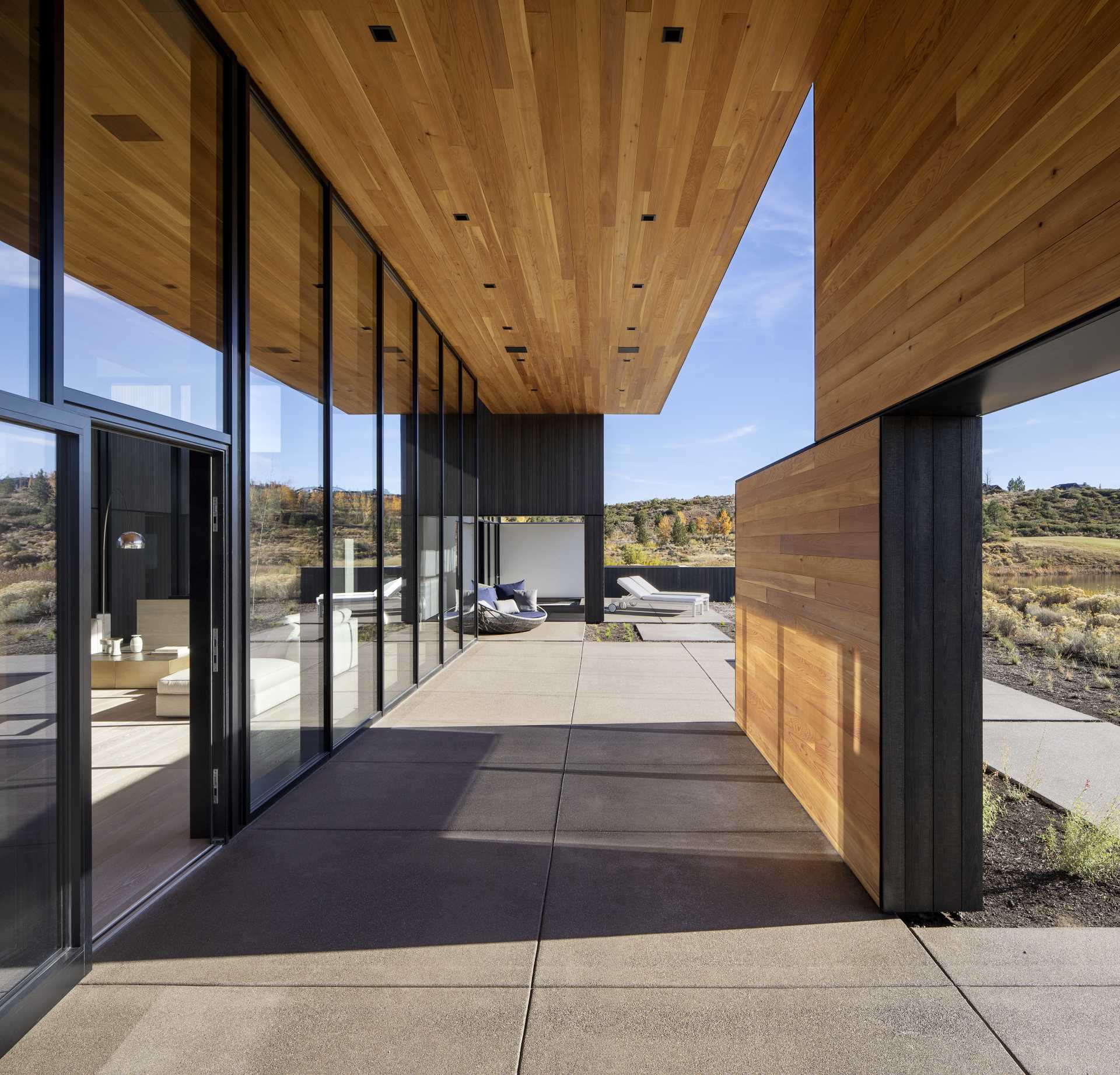 The covered patio of this modern home provides a place to enjoy the uninterrupted views.