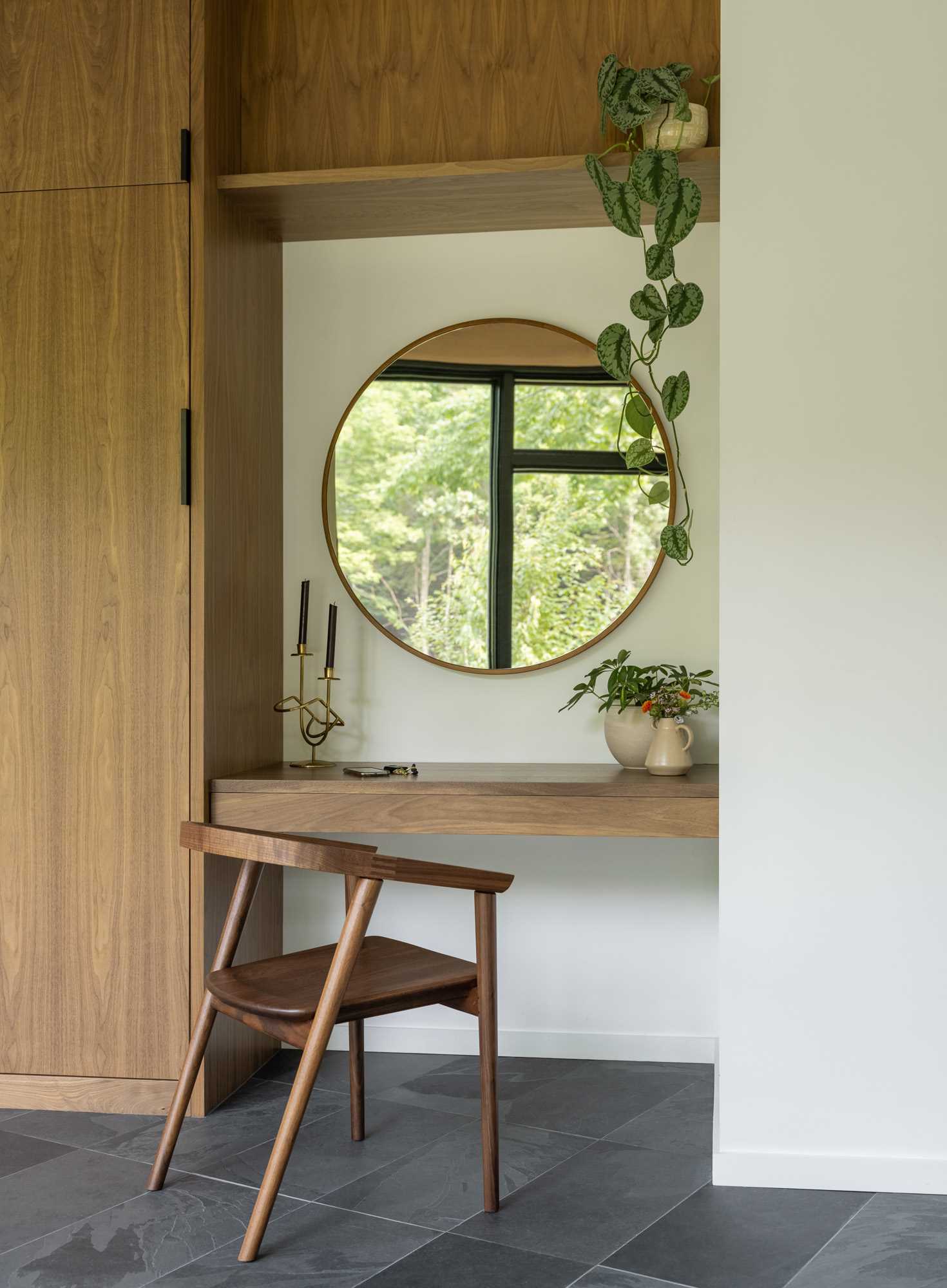 Inside this modern house, the entryway includes a small built-in desk area with a round mirror, and closets.