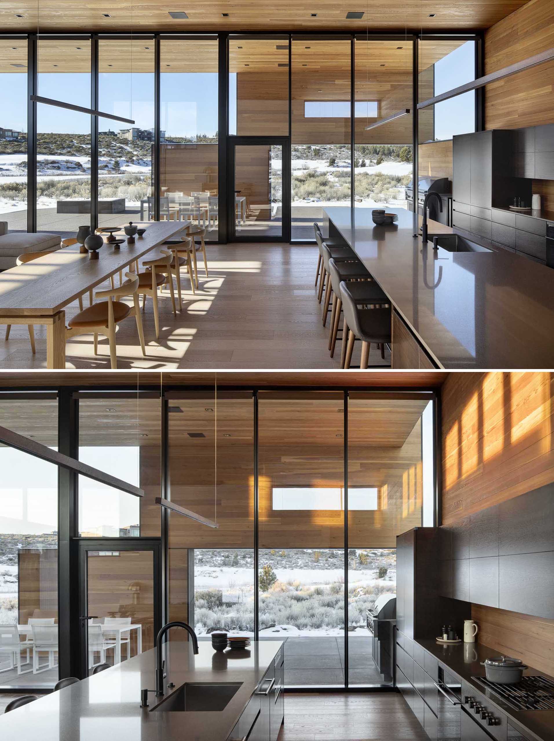 In this modern house with high ceilings, the dining area separates the living room from the kitchen, where black cabinets and a long island create a contrasting dark element to the open room.