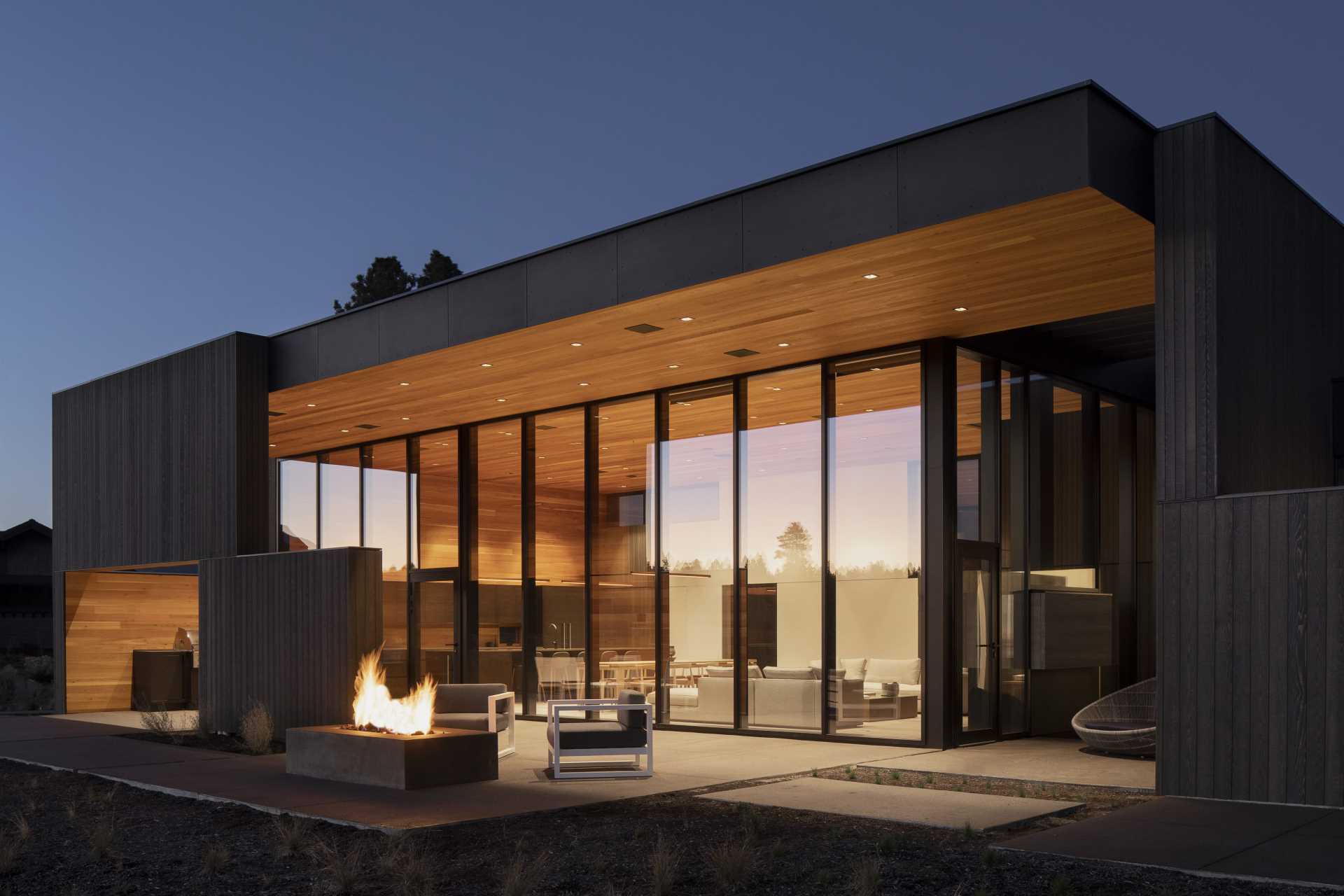 A modern house with cedar siding, high ceilings, and tall windows.