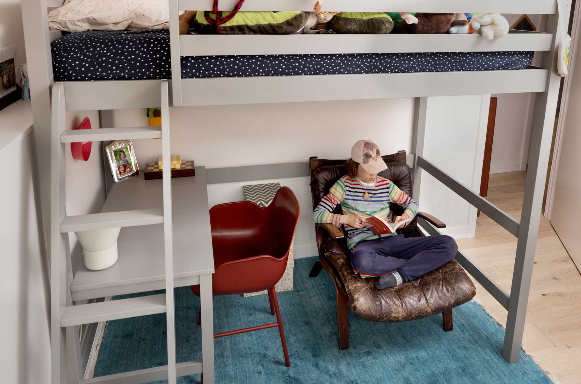A modern kids room with a lofted bed and desk.