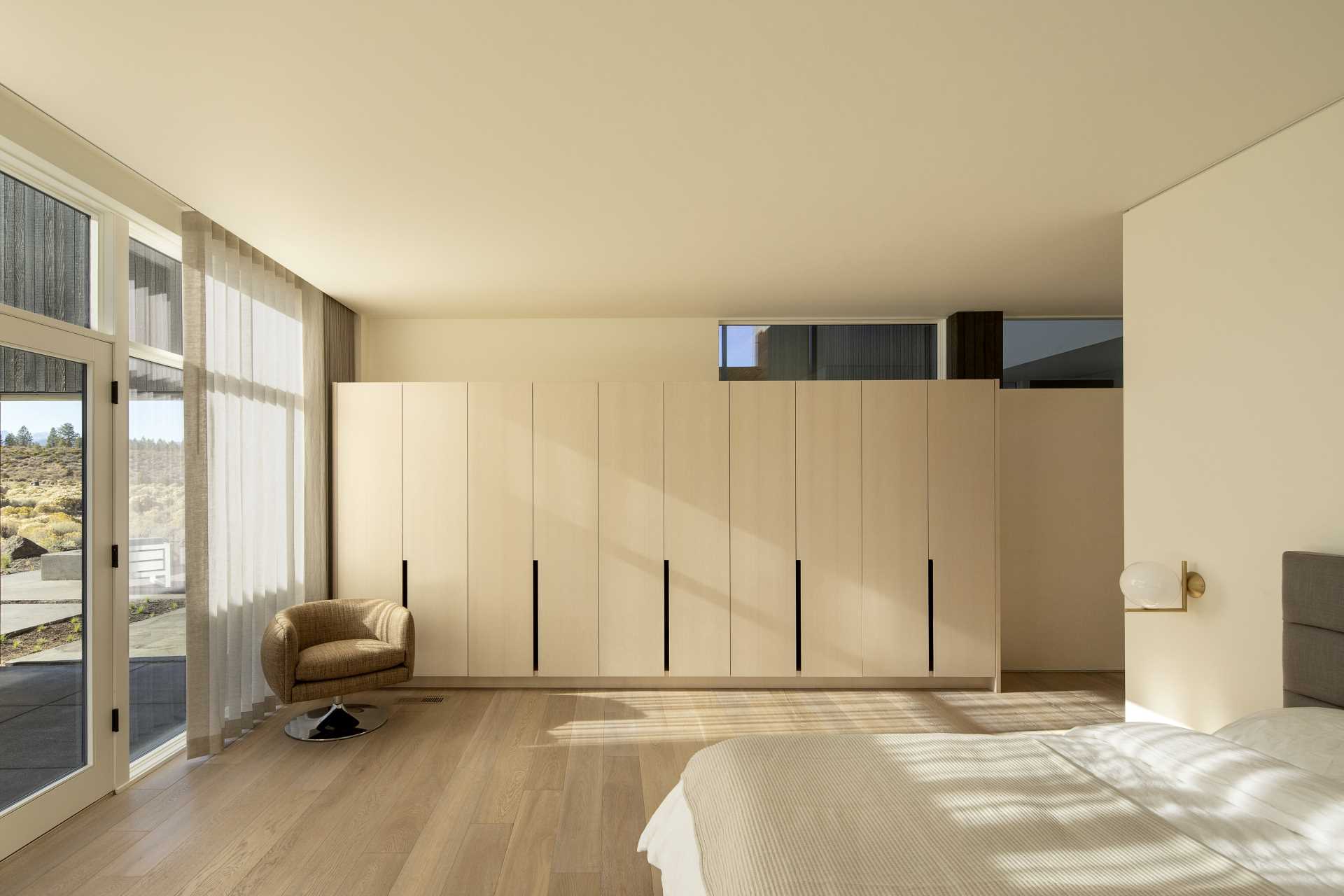 In this modern bedroom, light wood cabinets complement the light walls, floors, and bedding.