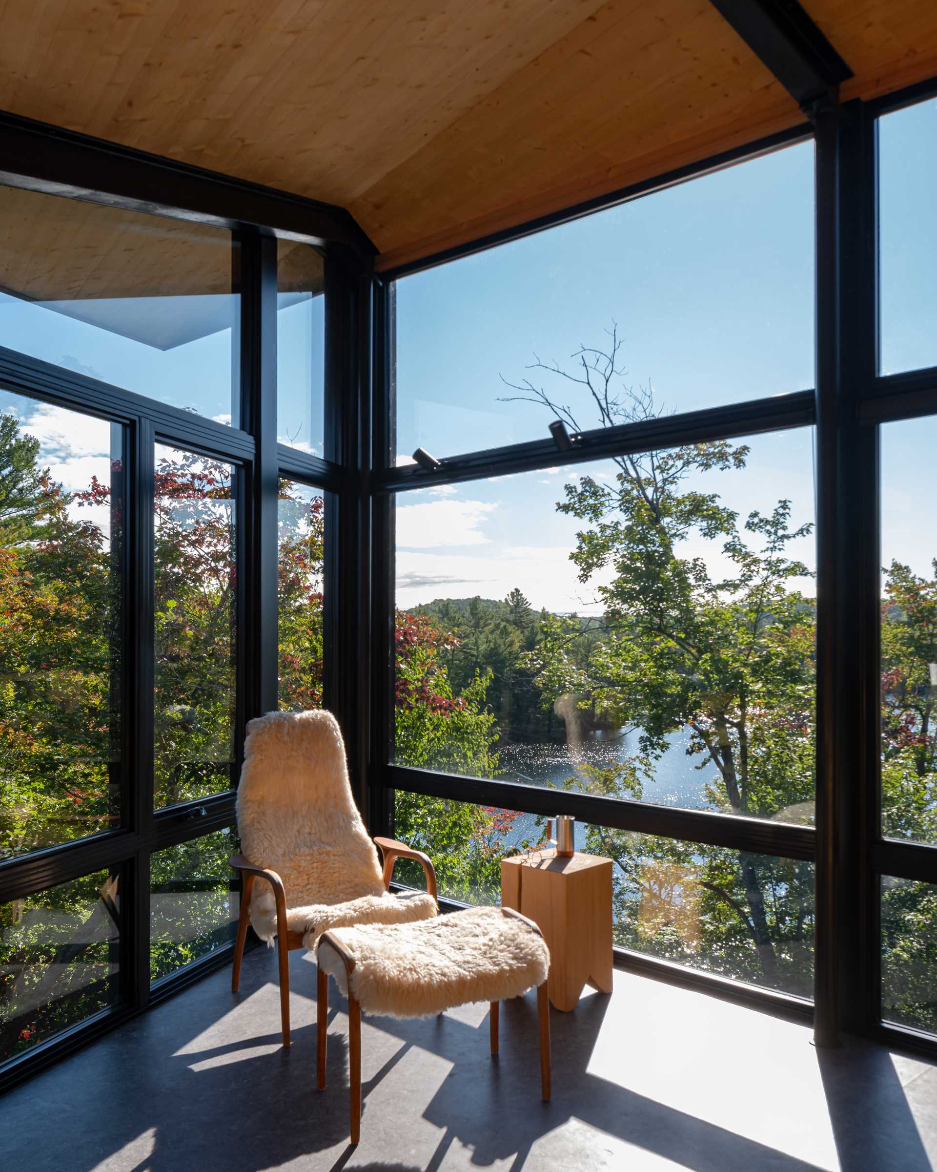 The interior of this modern cabin is lined with wood, however the black-framed windows, which travel the length of the cabin, provide views of the surrounding area.