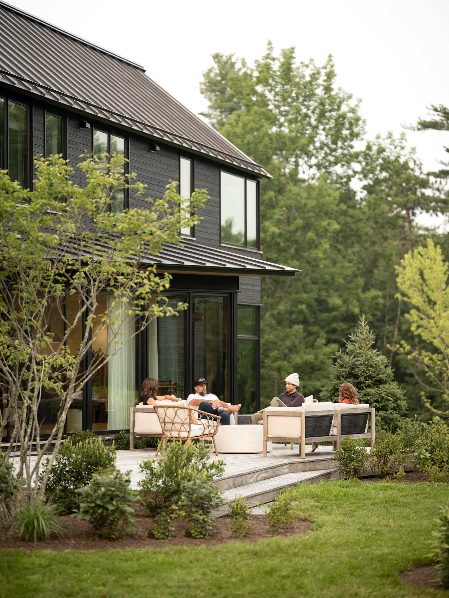 At the rear of this modern home, there's a wood patio furnished with comfortable seating, and steps that lead down to the garden.