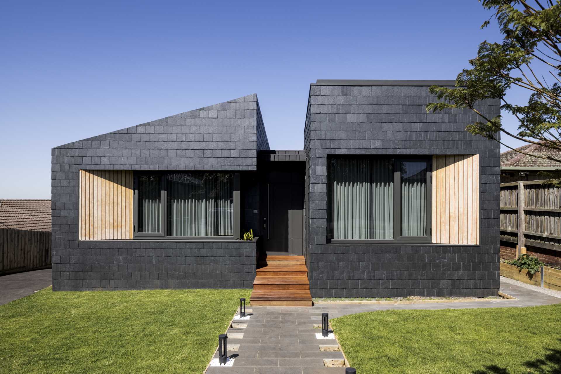 A modern home covered in black slate shingles and wood accents.