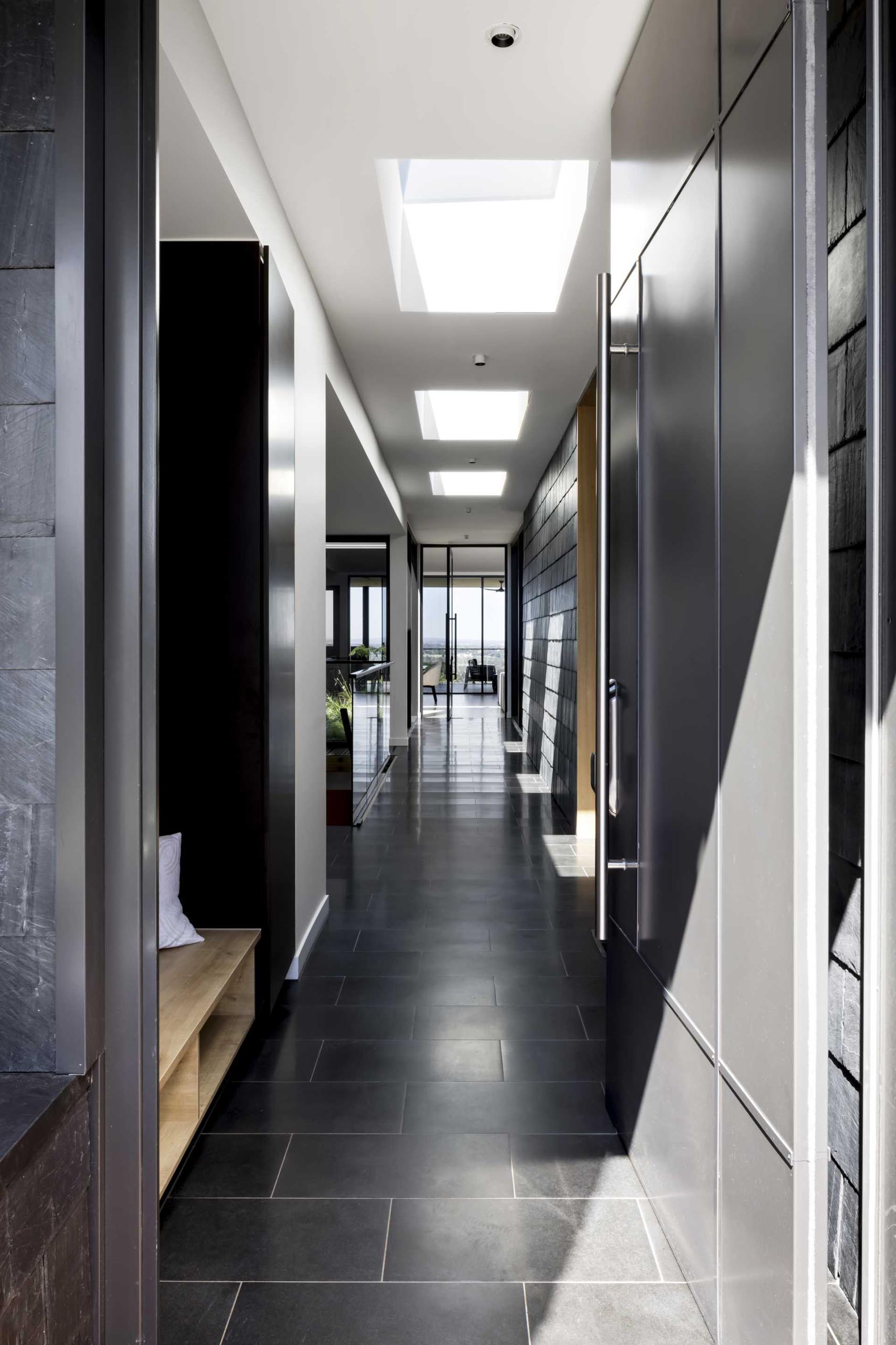 A modern house with a hallway that has black slate shingles and black tile flooring.