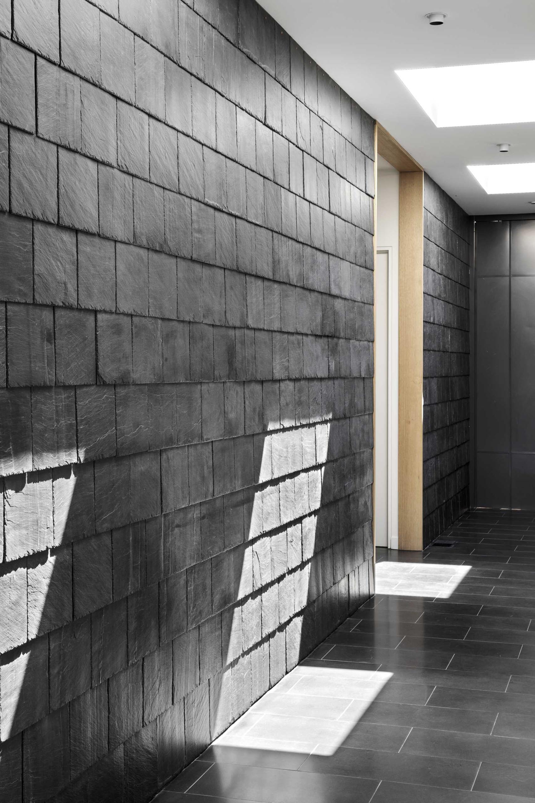 A modern interior with a hallway that has black slate shingles and black tile flooring.