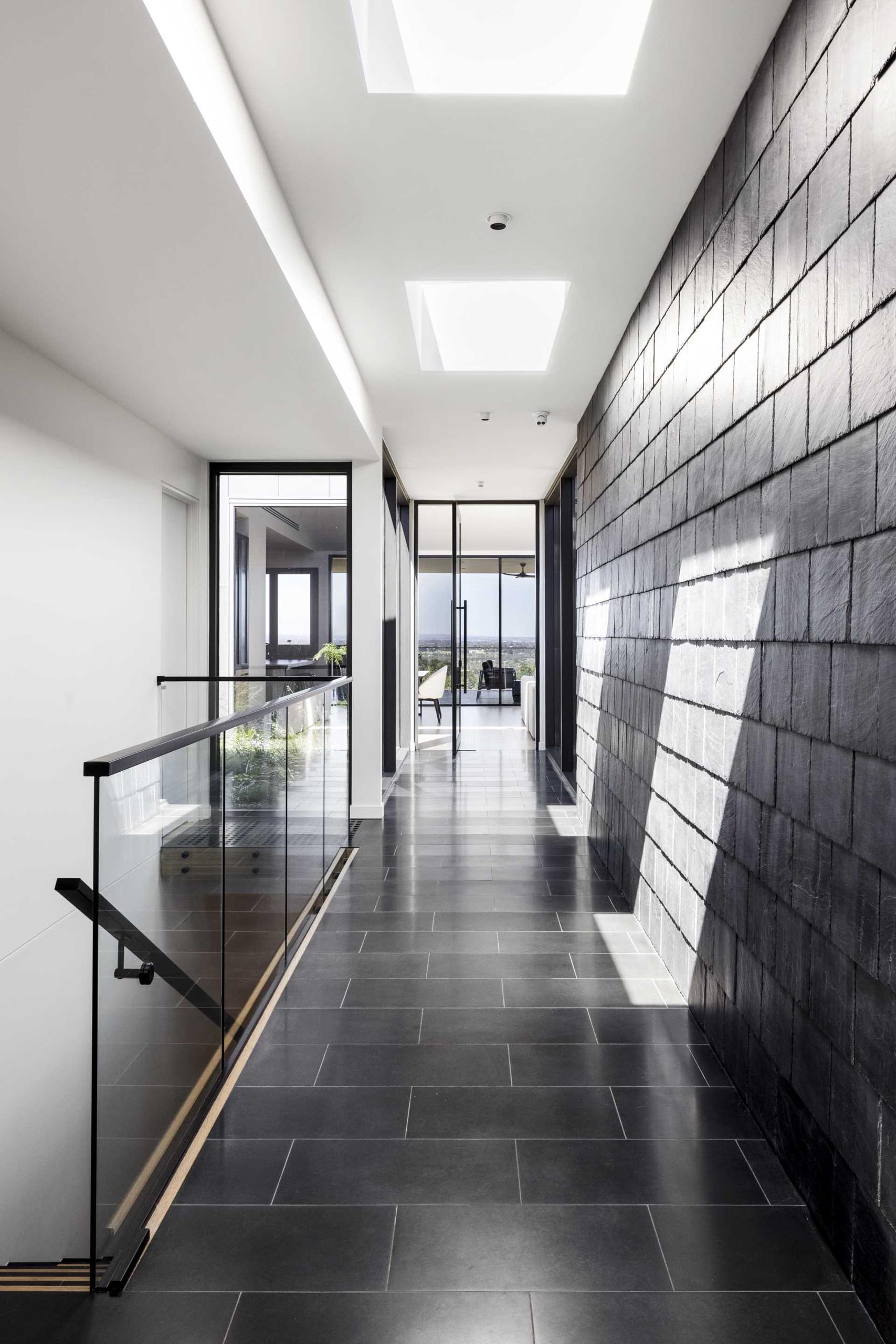 A modern hallway that has black slate shingles and black tile flooring.