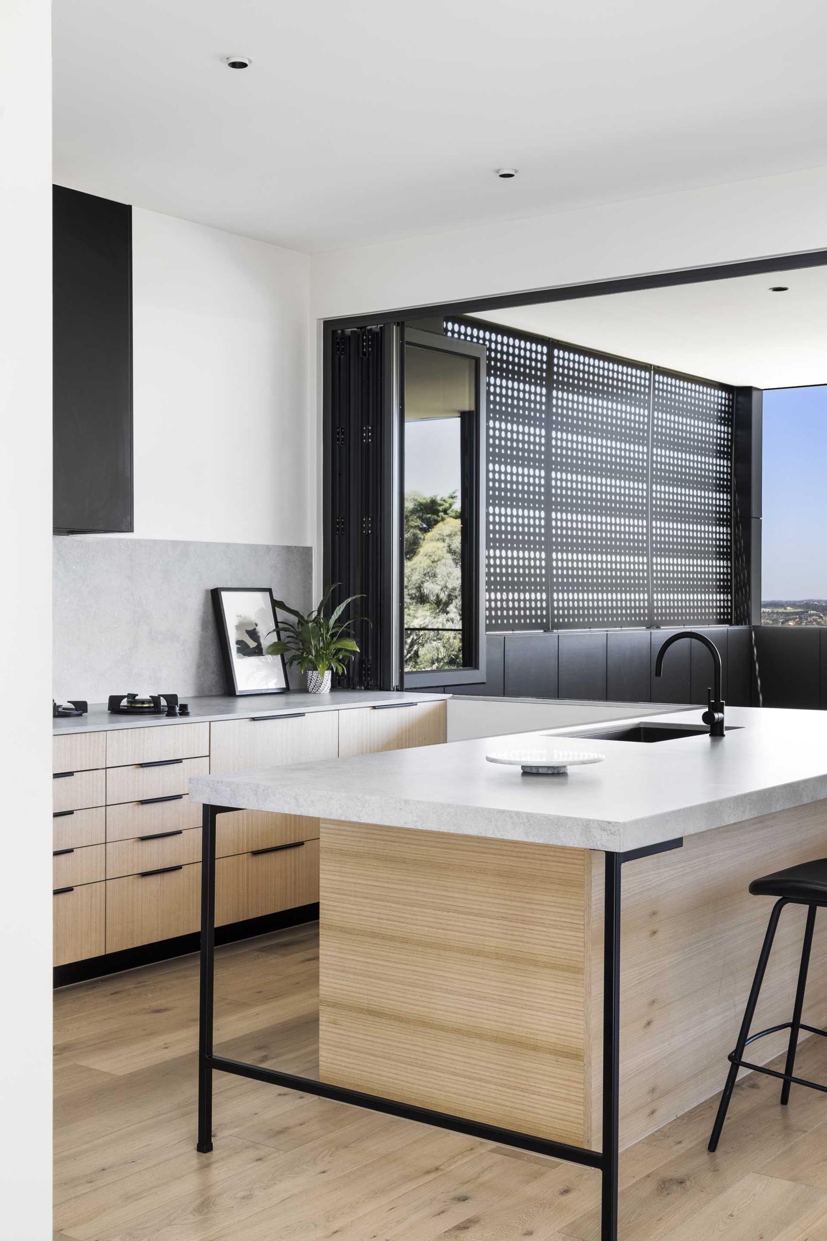 The minimalist kitchen includes both black cabinets and timber veneers in white Ash.