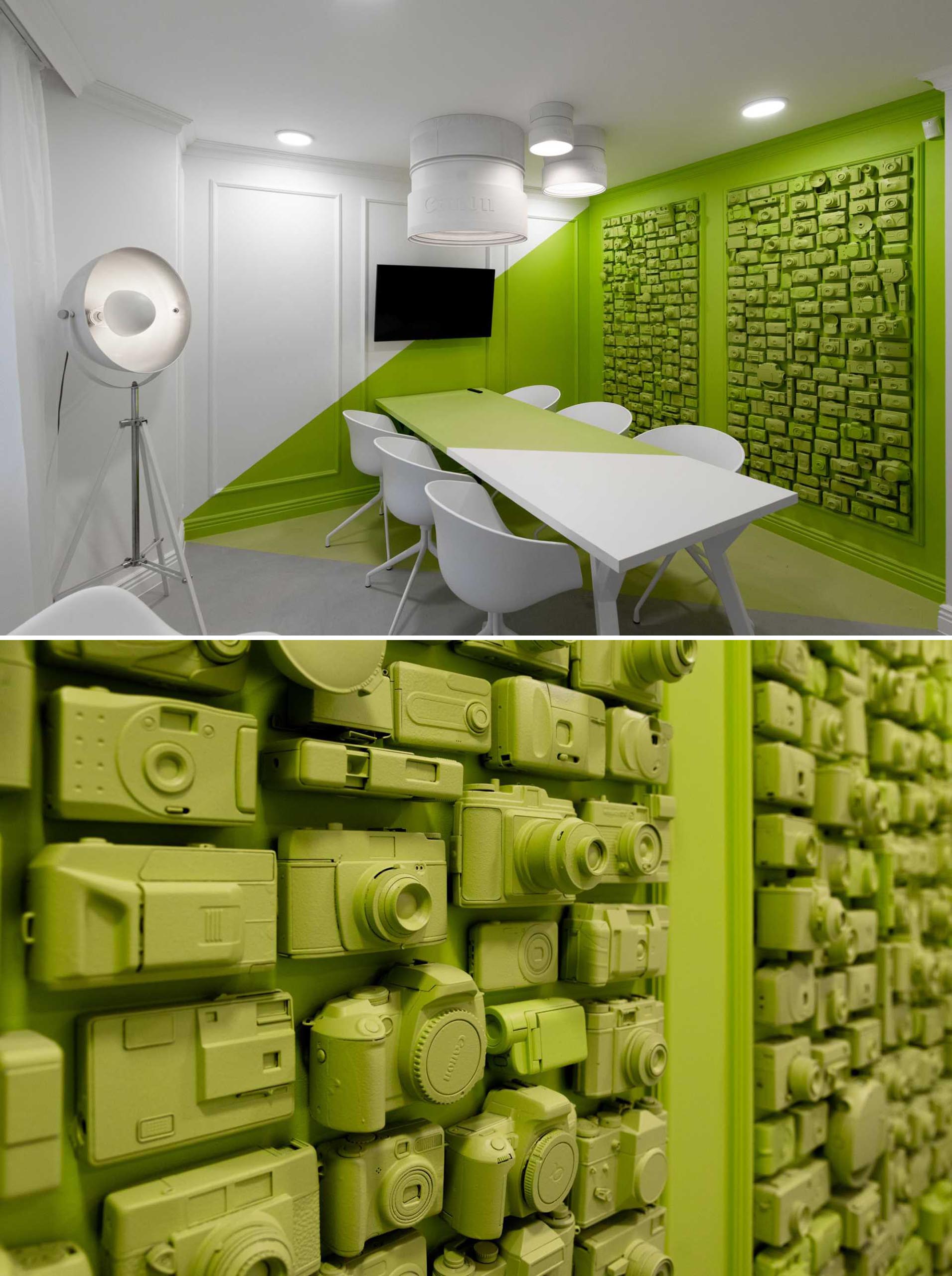 In this green meeting room, a wall featuring painted old cameras has been framed out as artwork, adding texture and interest to the room.