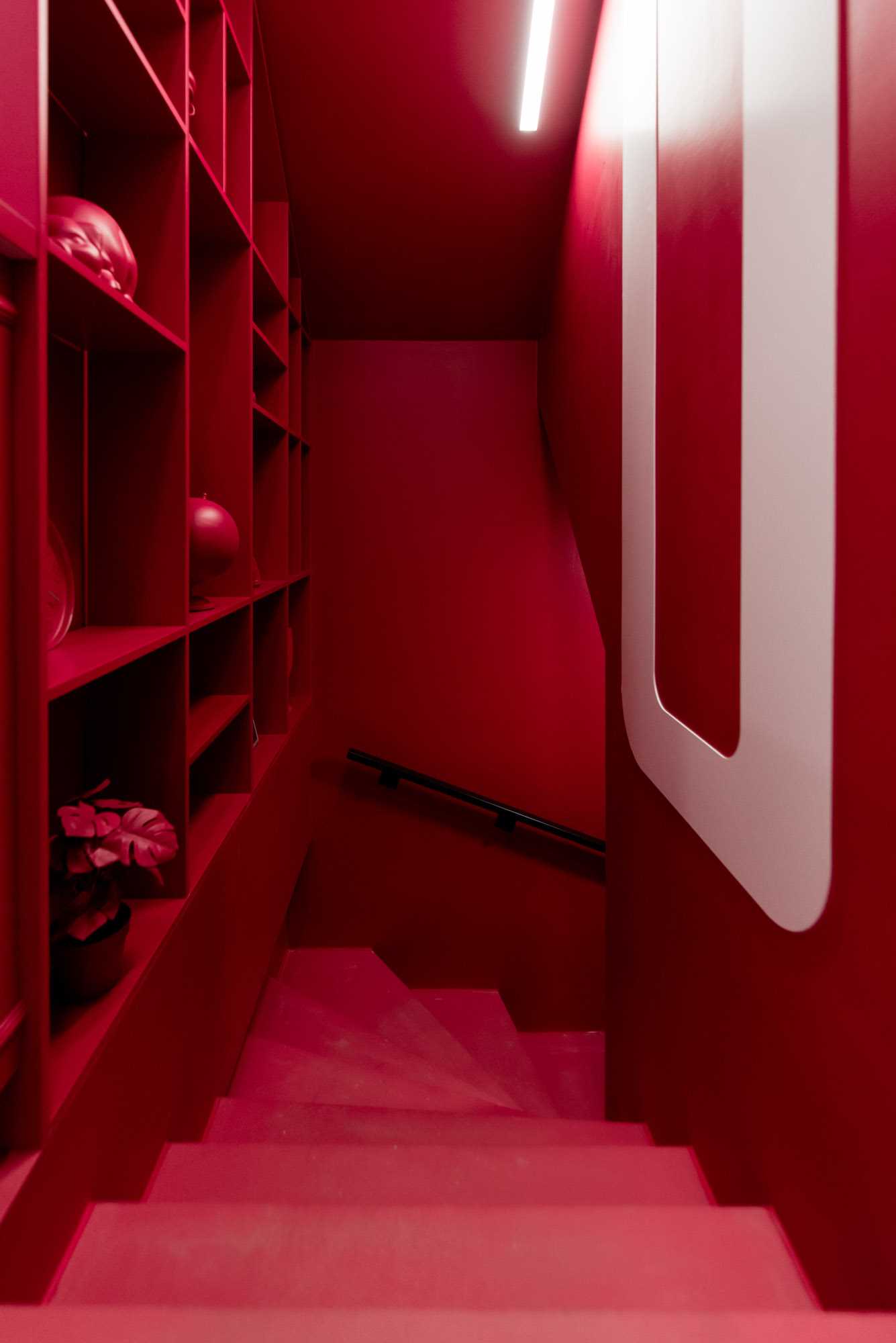 A bold red staircase with matching painted decor and shelving.