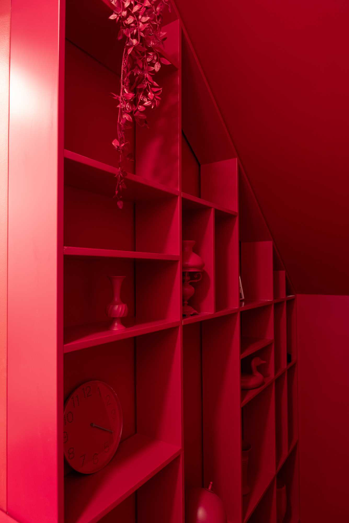 A bold red staircase with matching painted decor and shelving.