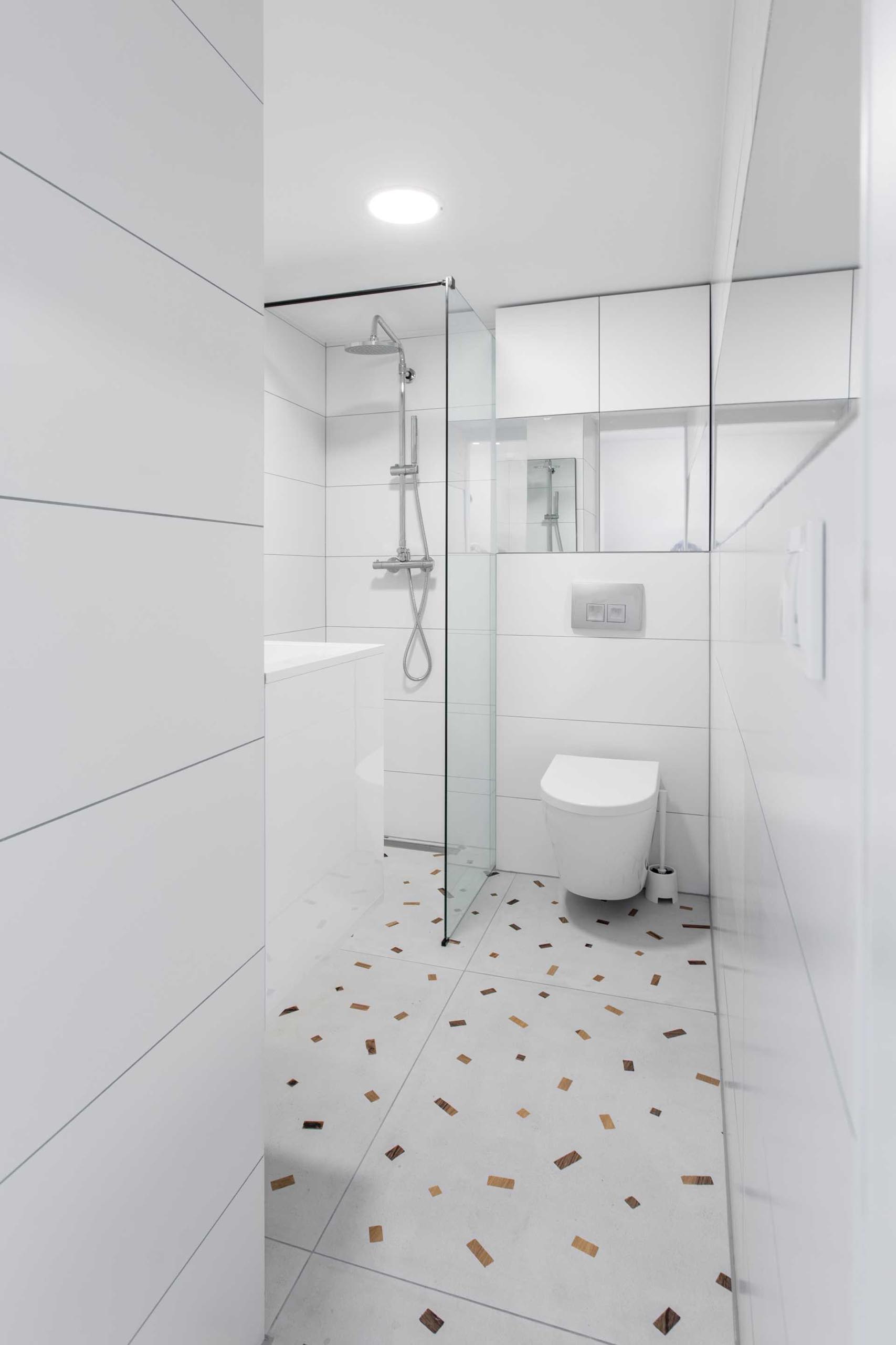 White walls keep this small bathroom bright, while flecks on the floor add a colorful element.