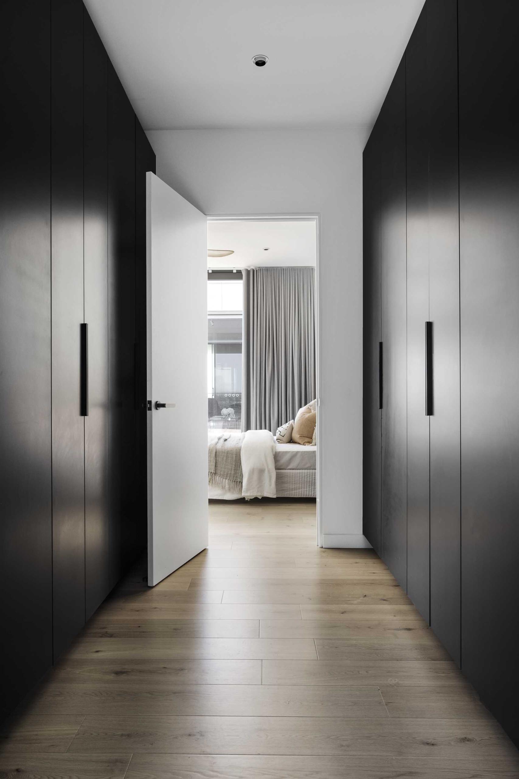 A walk-in closet has tall black closets that provide plenty of storage space.