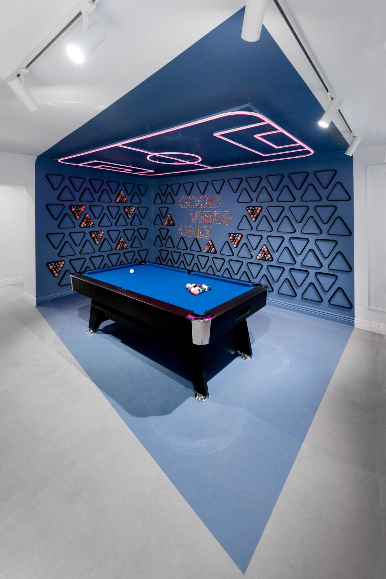 In this office break room, blue was chosen as the accent color, and it's been furnished with a billiard table, a neon accent light on the ceiling, and walls filled with billiard accessories.