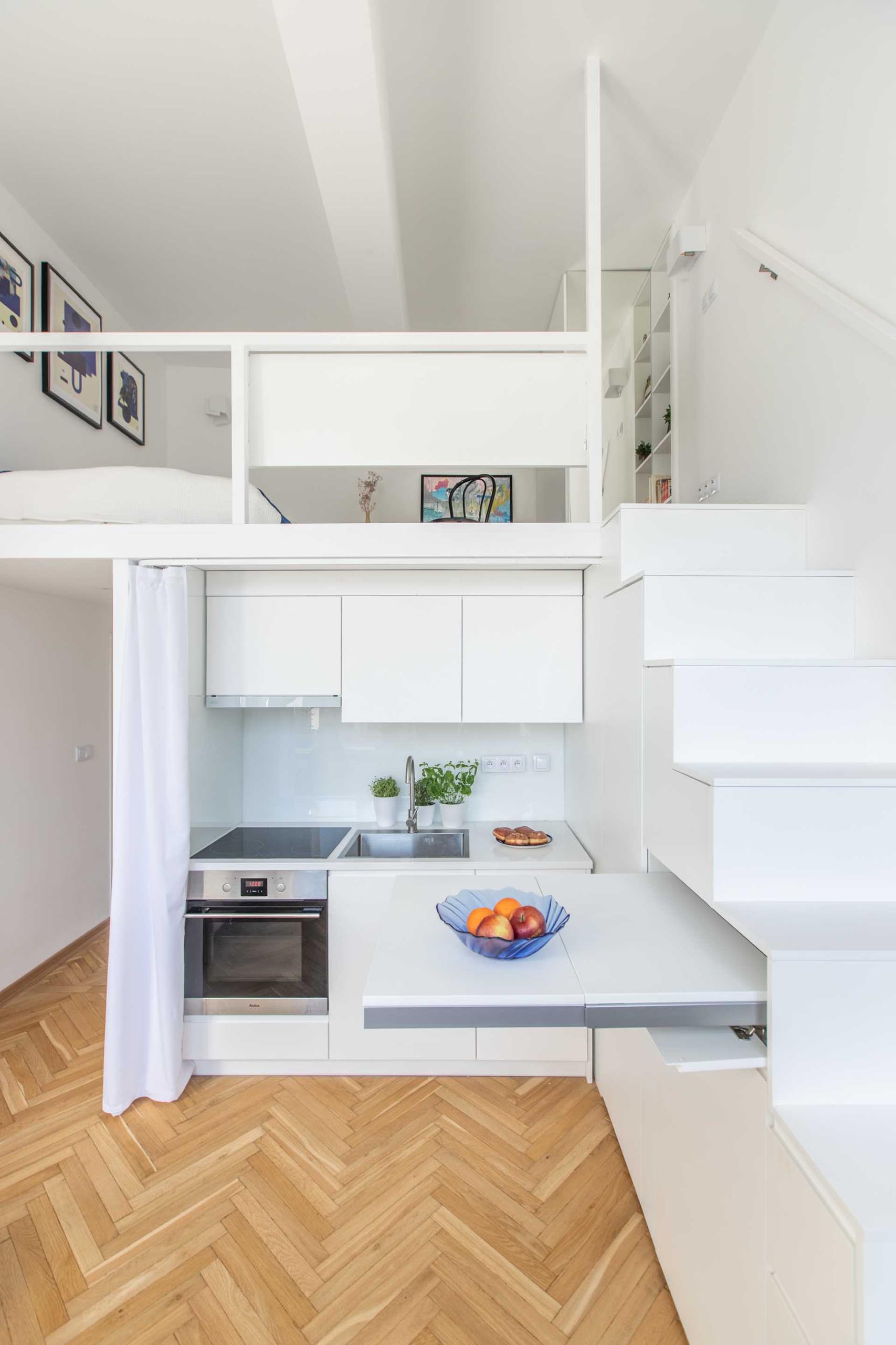 A small apartment has a pull-out table underneath the stairs.
