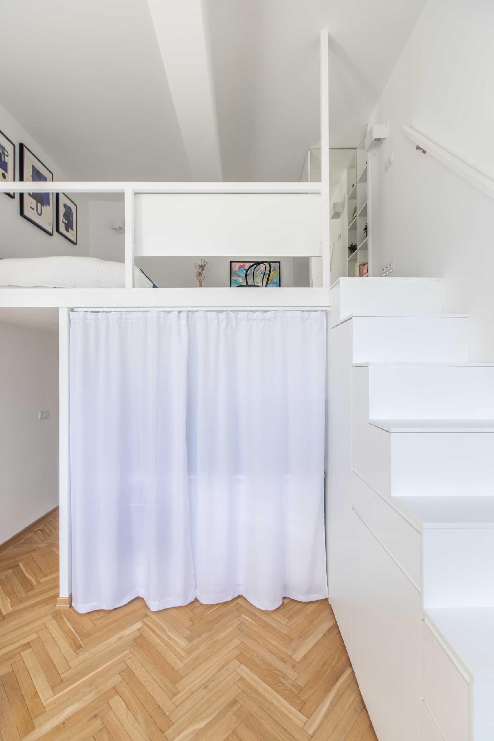 A small apartment has a kitchen that can be hidden by a curtain.