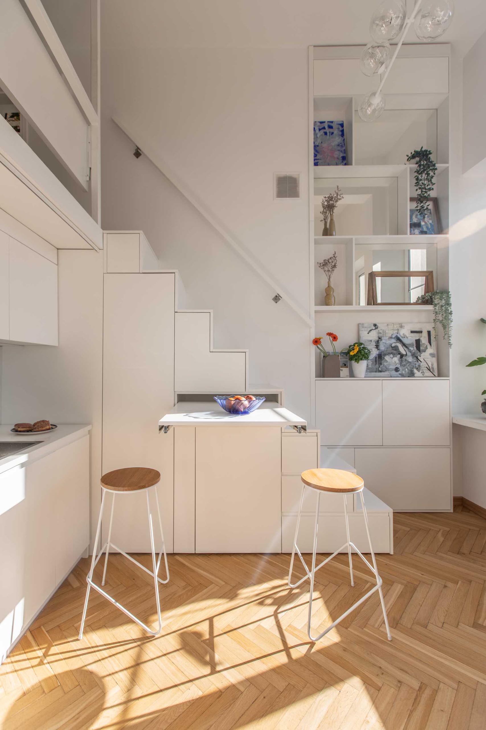 A small apartment has a pull-out table underneath the stairs that acts as a dining table or additional countertop.