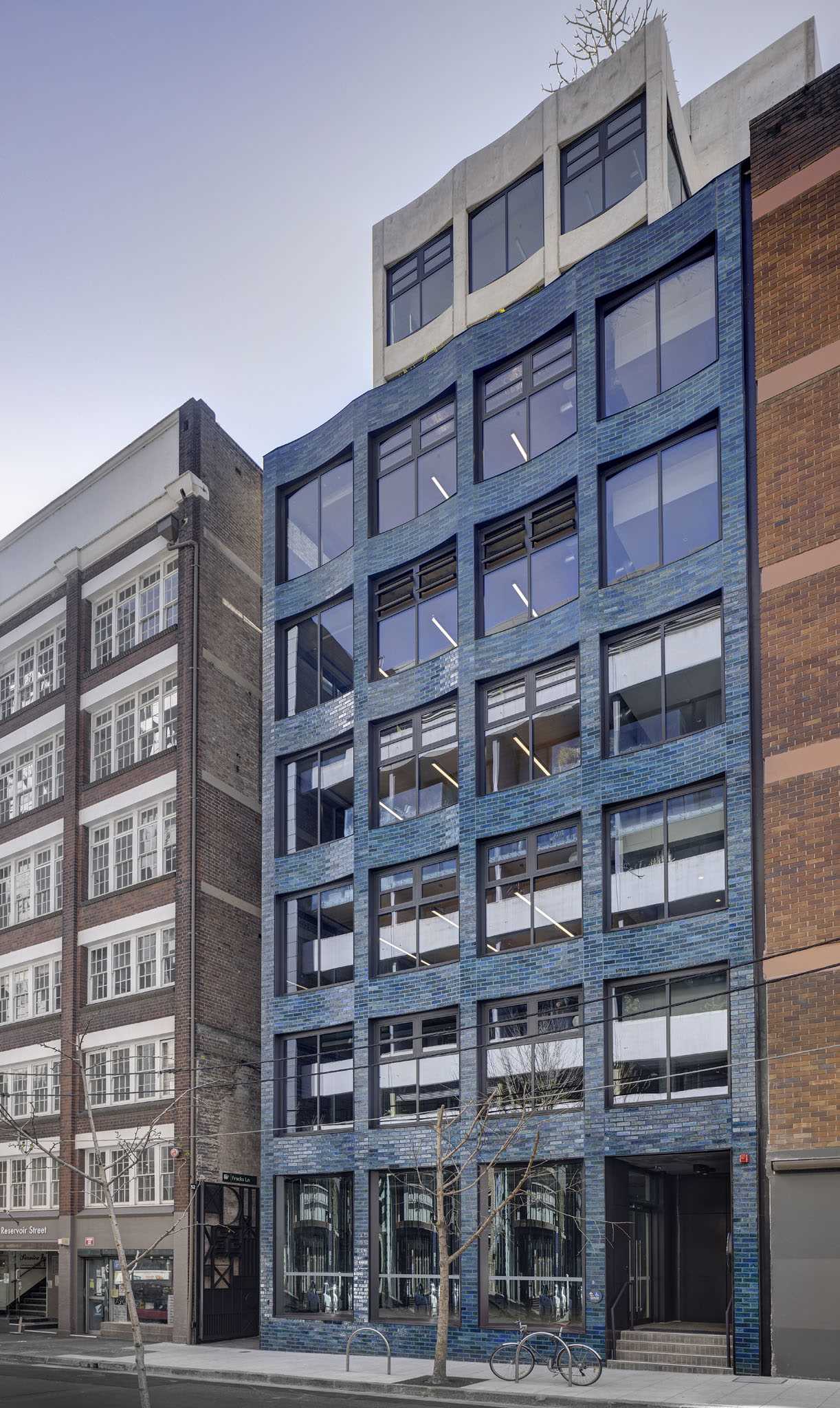 A modern commercial building with a scalloped facade and aquamarine glazed bricks.