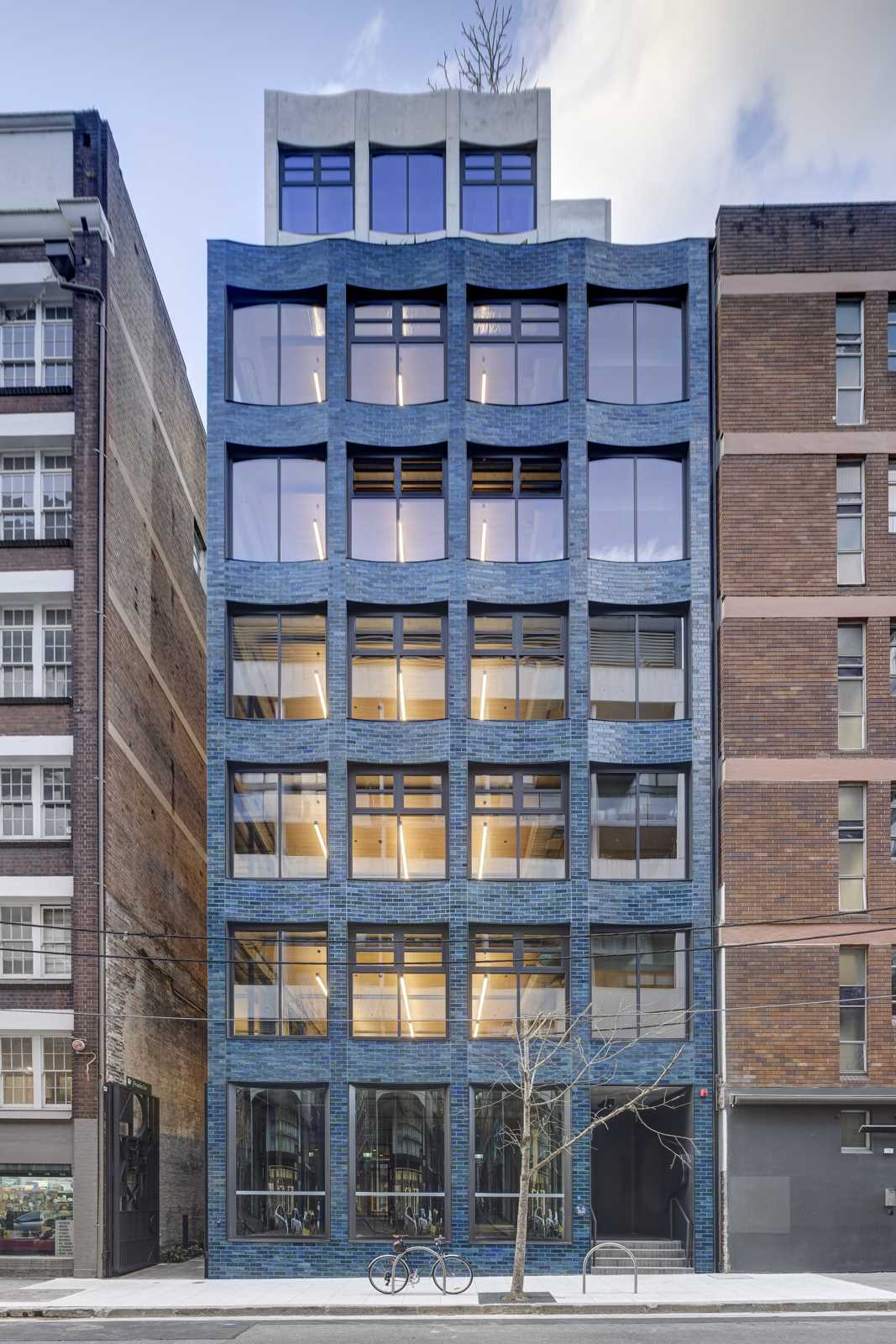 A building with a scalloped facade and aquamarine glazed bricks.