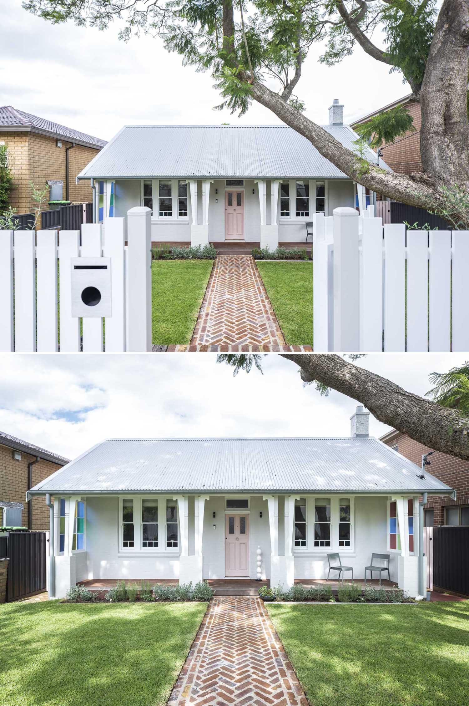This cute cottage has a front white fence, a brick path, and a porch that runs across the front of the house.