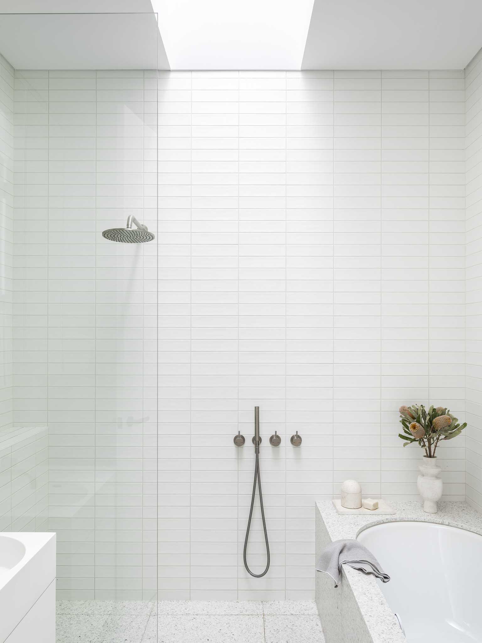 A modern bathroom with a built-in bathtub and tiled walls.