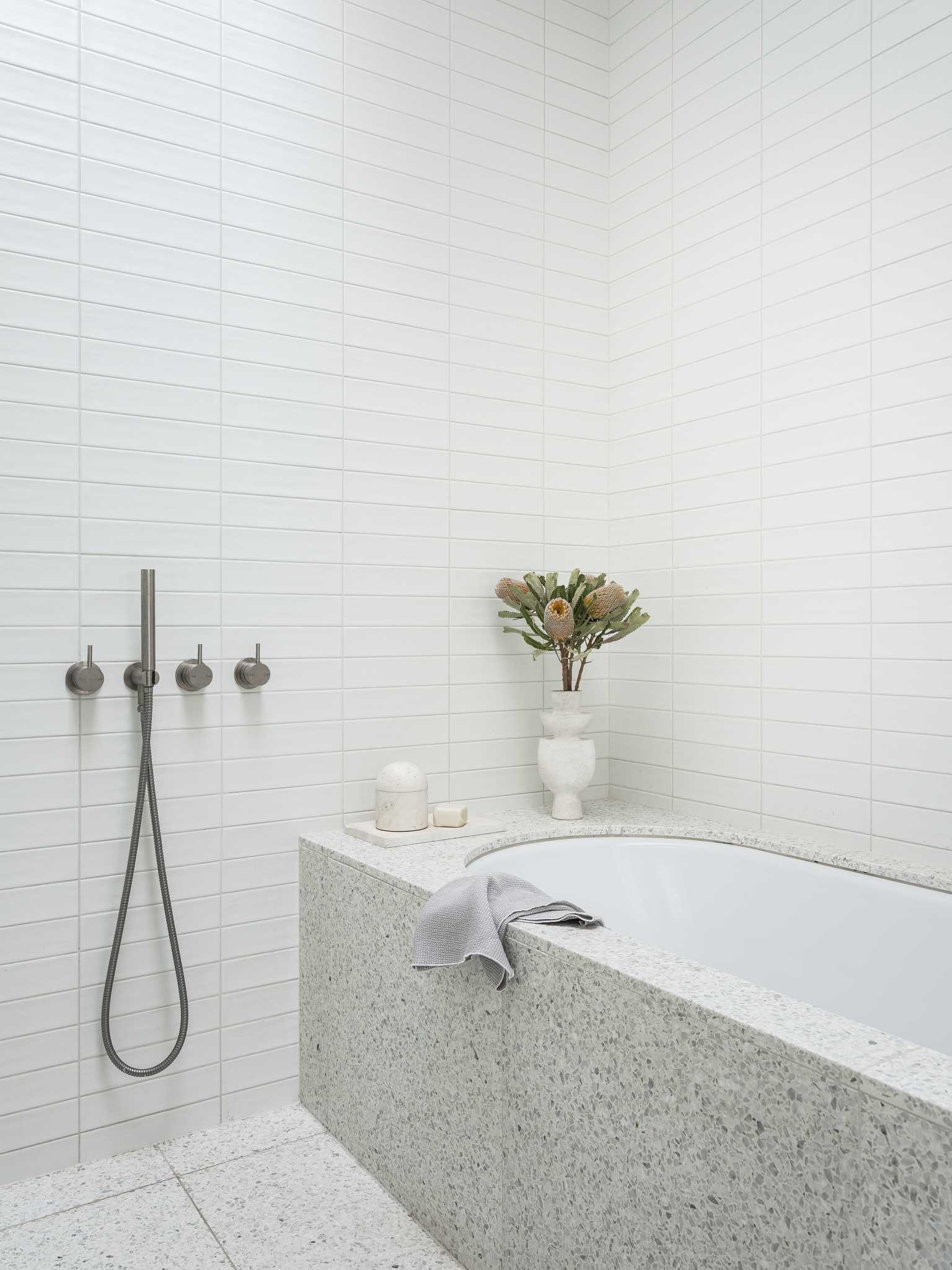 A modern bathroom with a built-in bathtub and tiled walls.