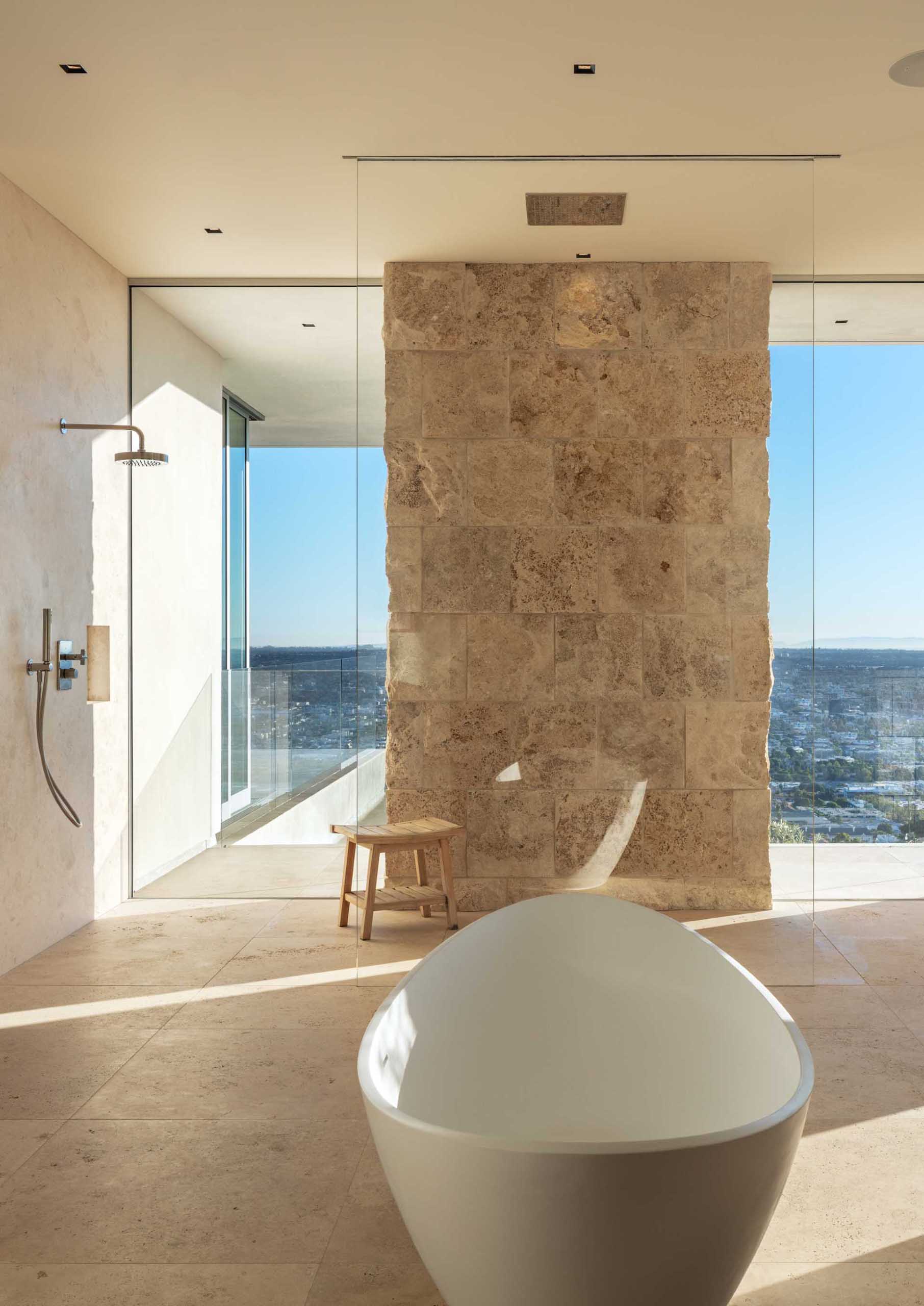 A modern bathroom with a freestanding bathtub and shower by the windows.