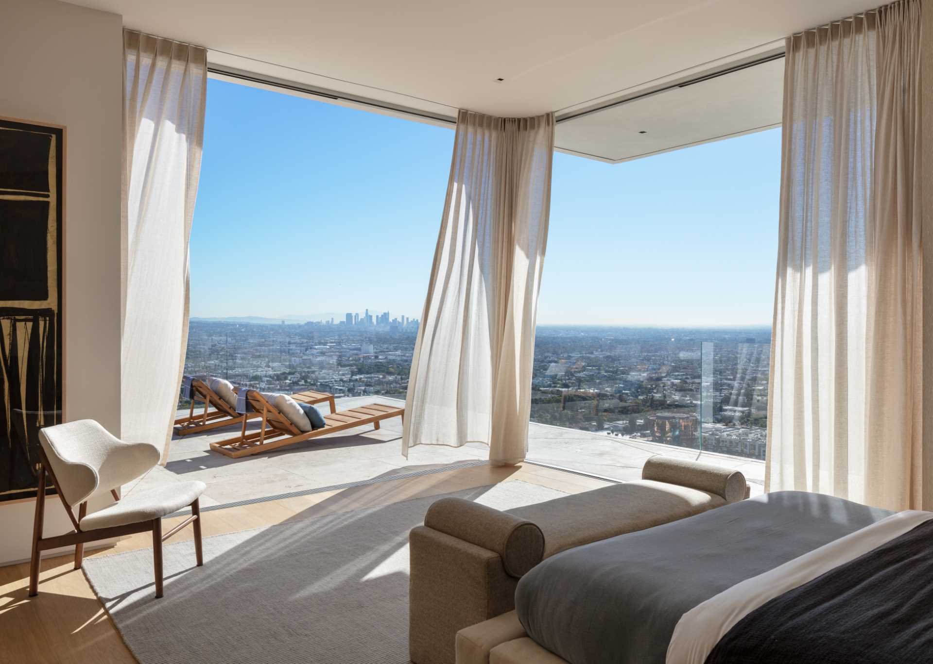 A modern bedroom with floor-to-ceiling windows and a private balcony.