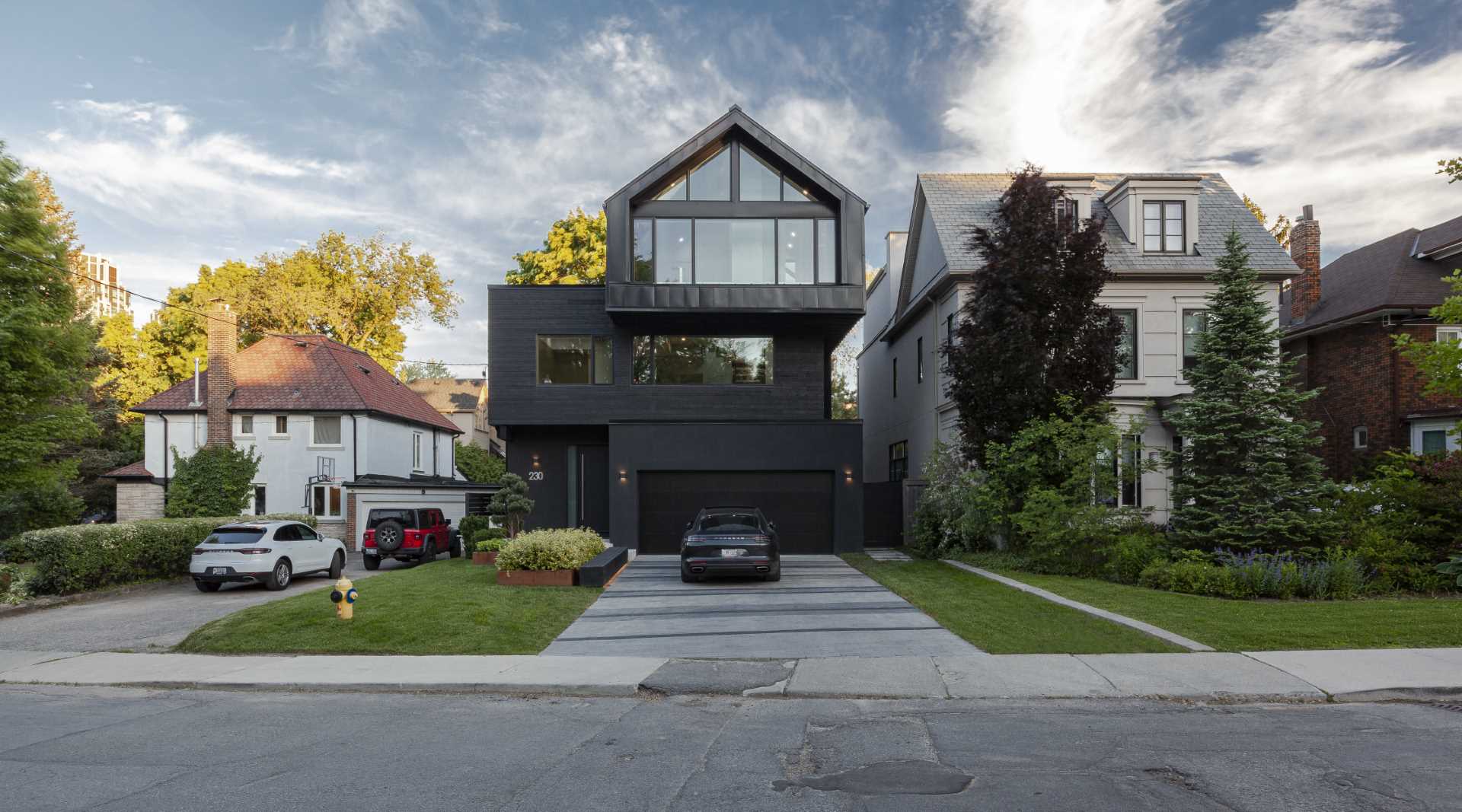 A modern home with three stacked volumes, has a dark grey exterior. 