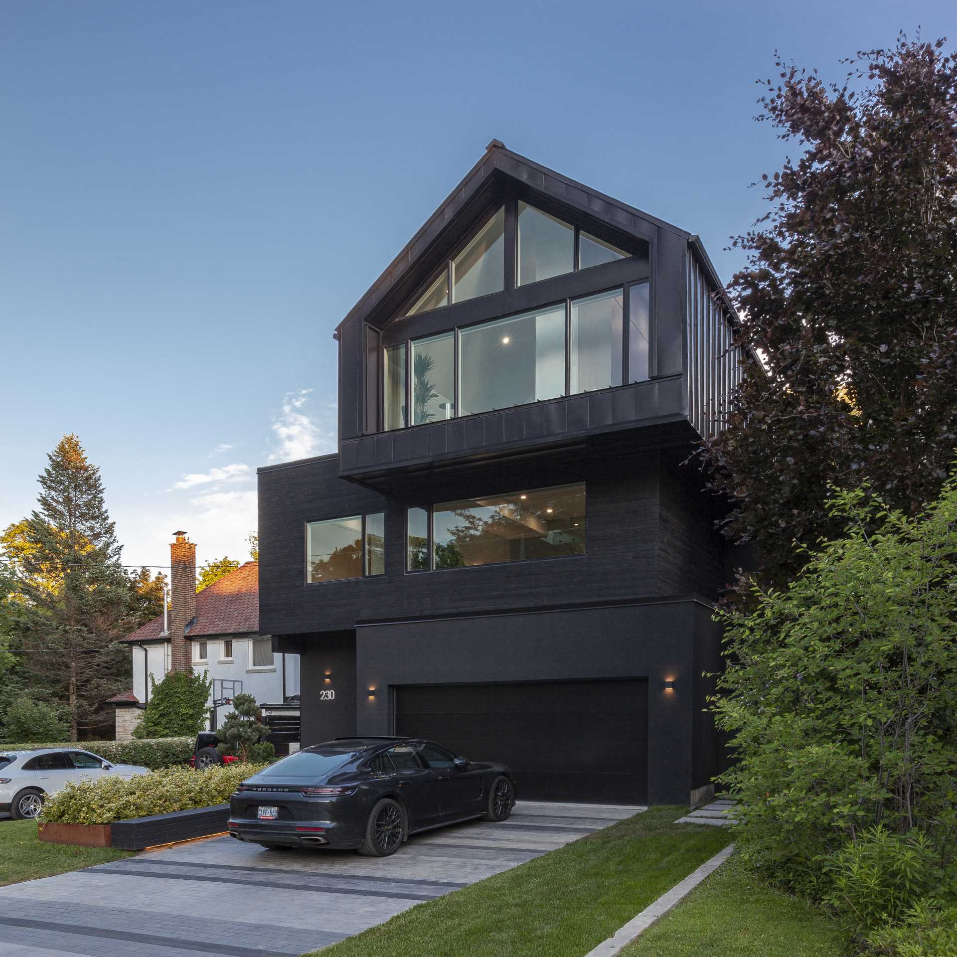 A modern home with three stacked volumes, has a dark grey exterior. 