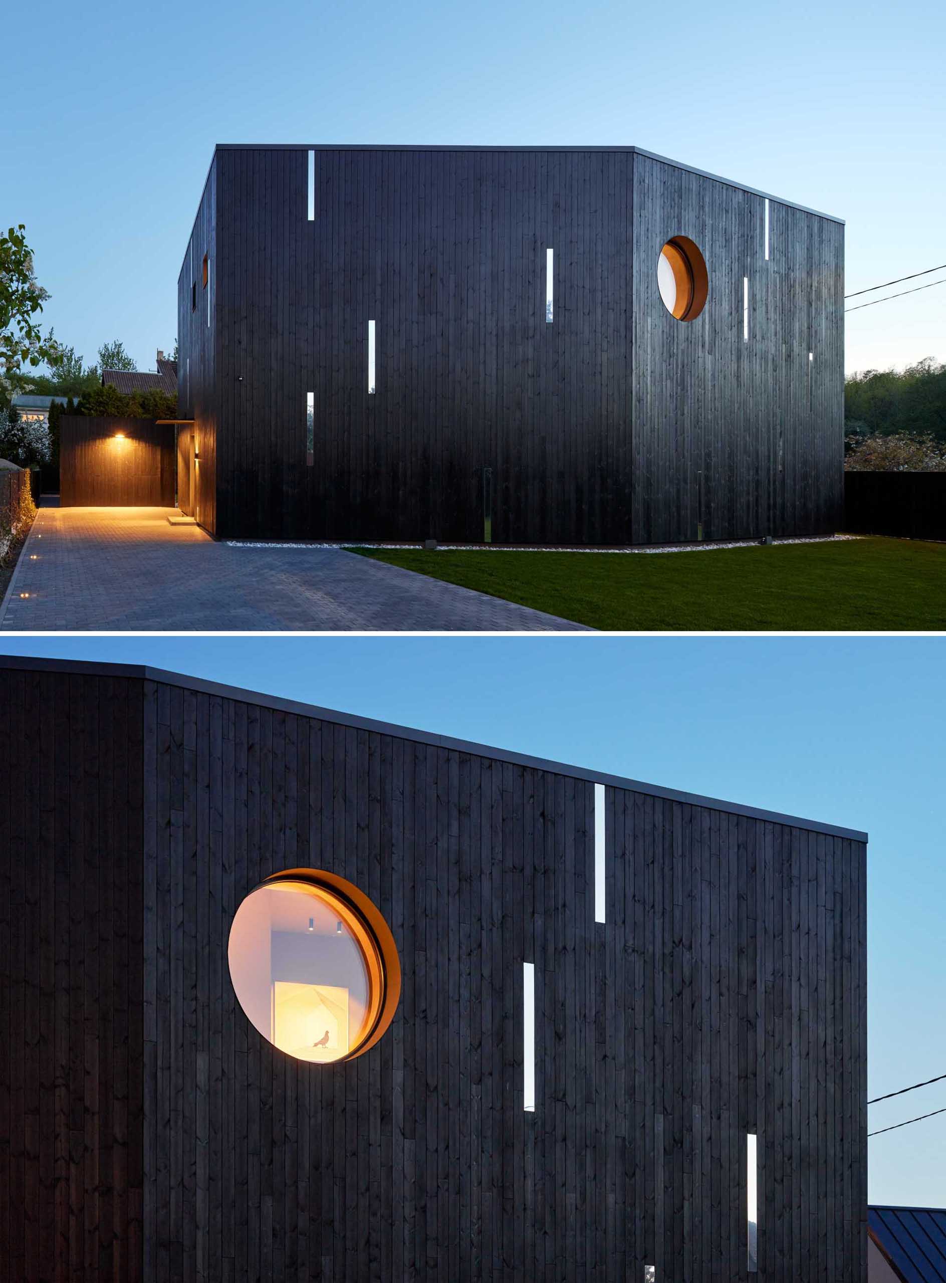 A modern house with a black wood exterior and mirrored accents.