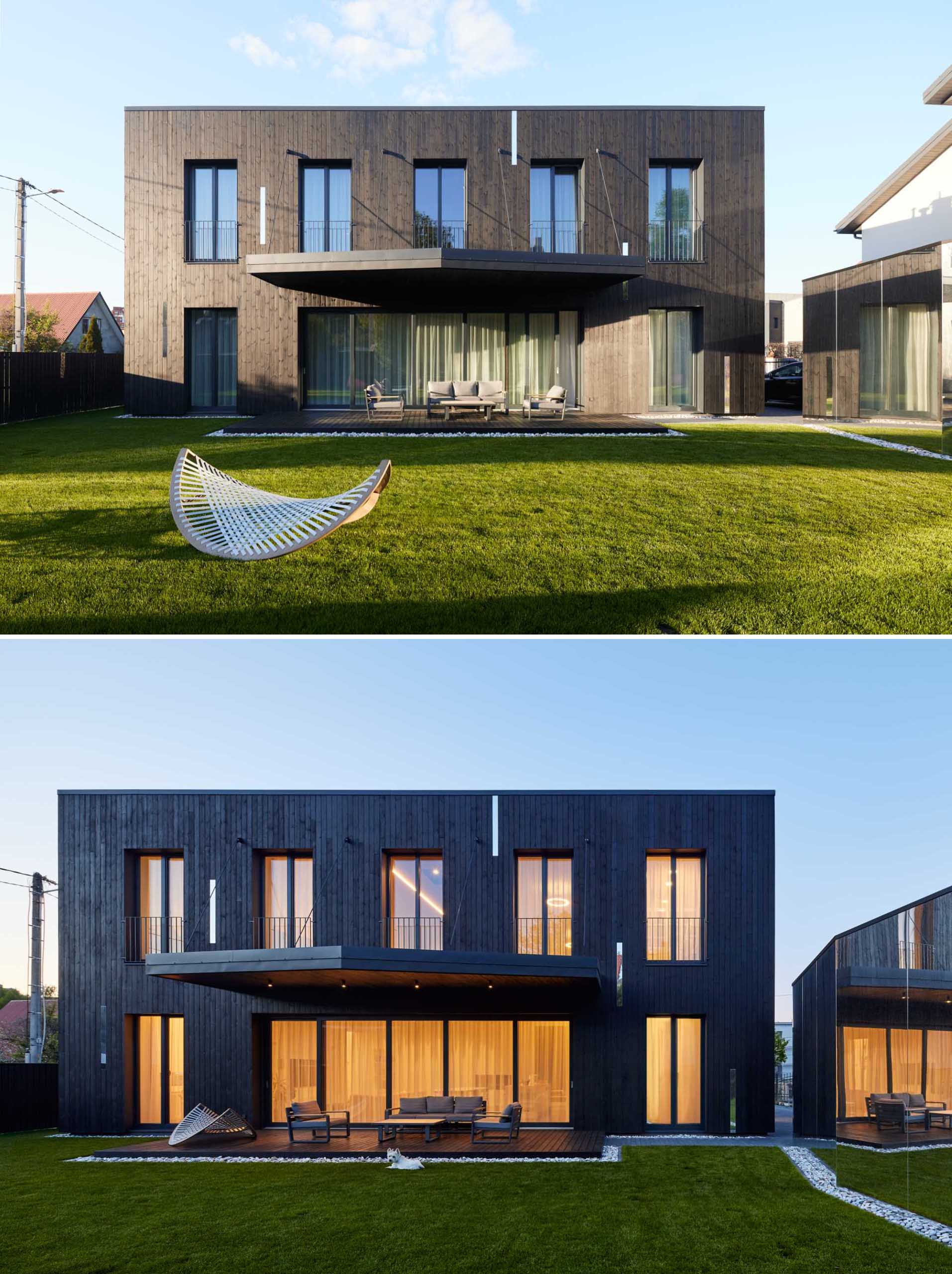 The rear of this modern home includes a covered patio that has a view of the yard and the garage.