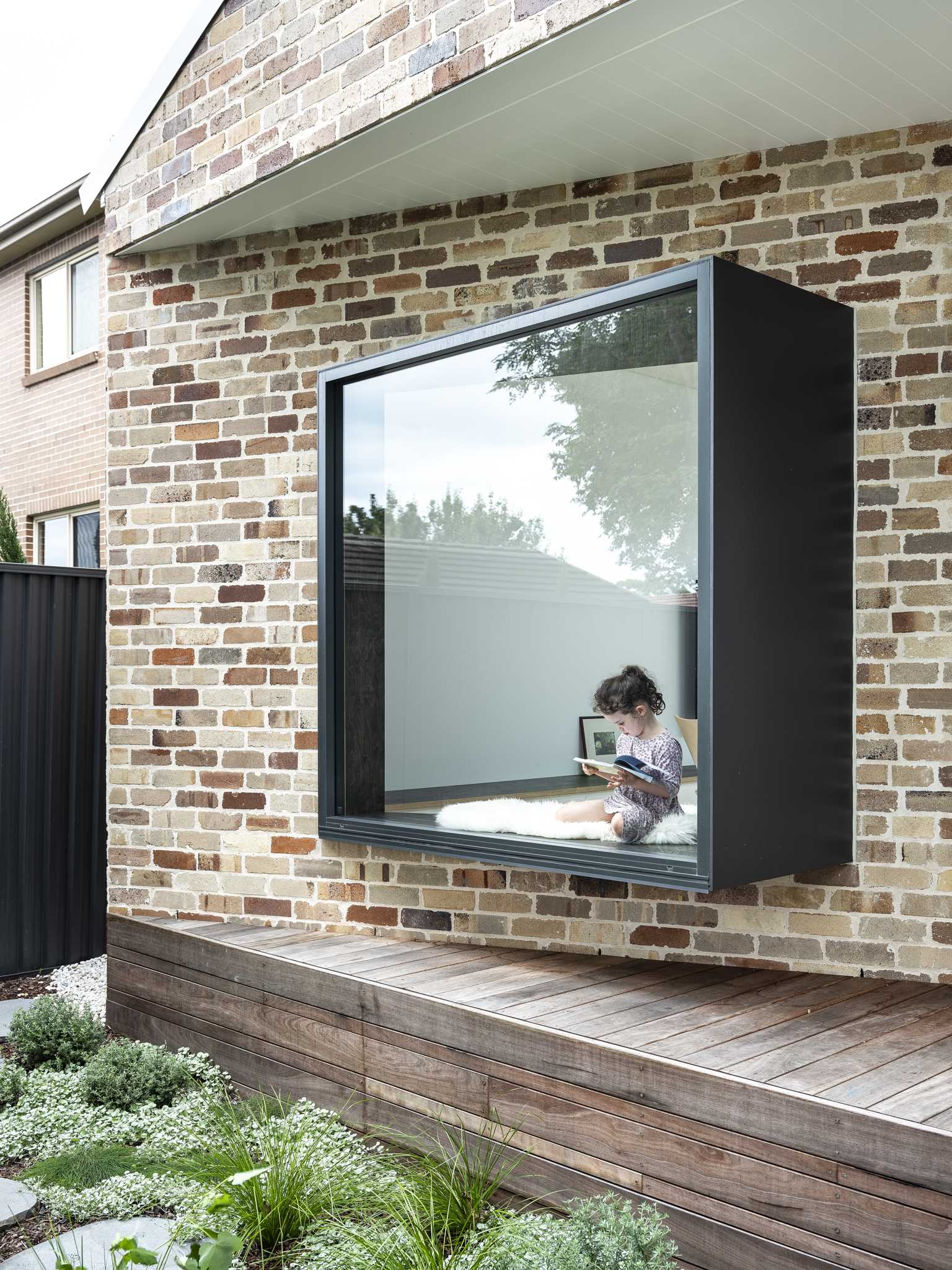 A modern recycled brick addition with an angled window seat that protrudes away from the wall.