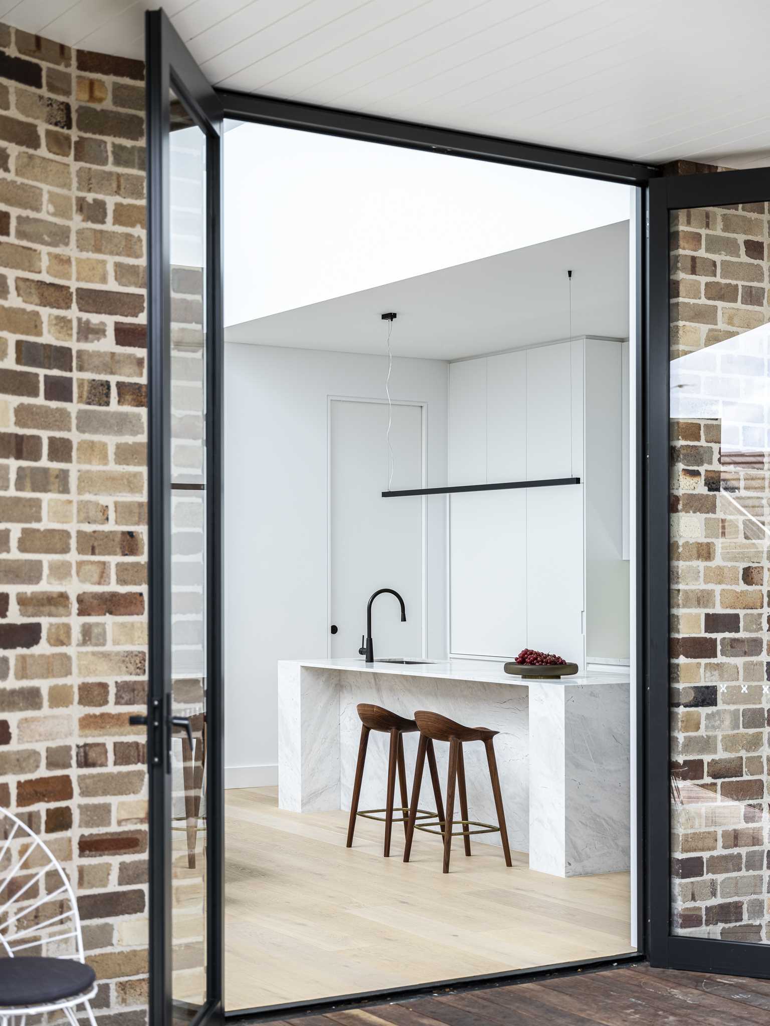 A brick addition has black framed glass doors.