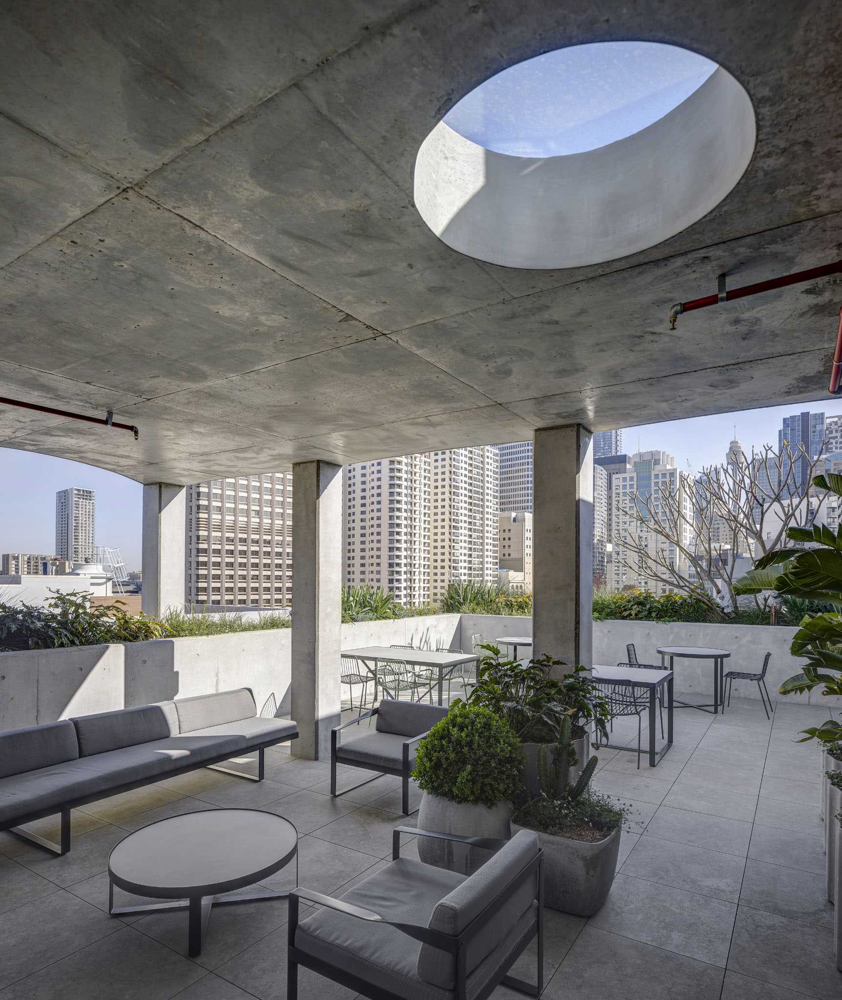 A rooftop patio with built-in concrete planters wrapping around the exterior, and multiple different seating areas.