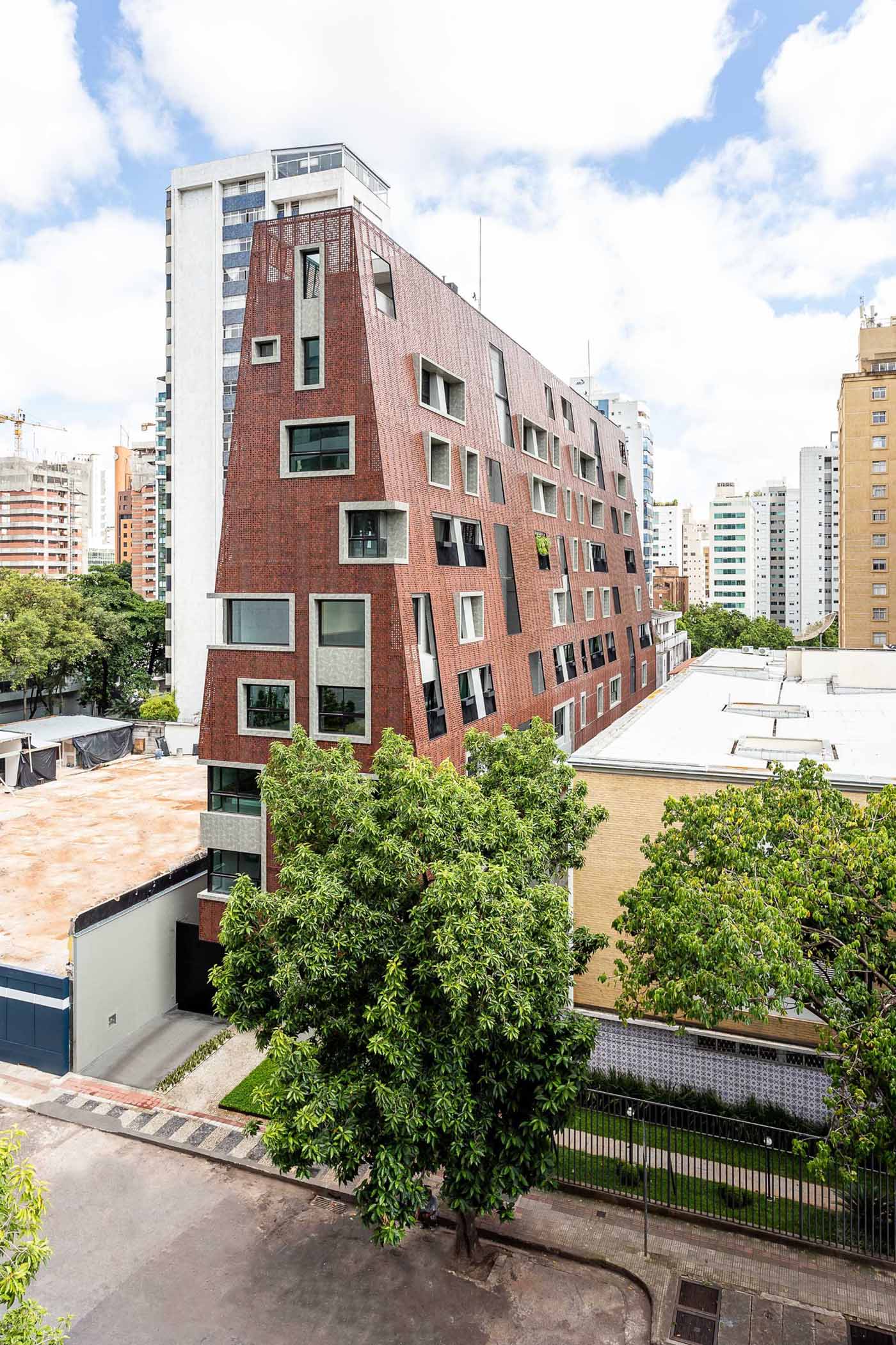 A residential building is covered in perforated aluminum panels, each painted in an earthy reddish sepia tone.