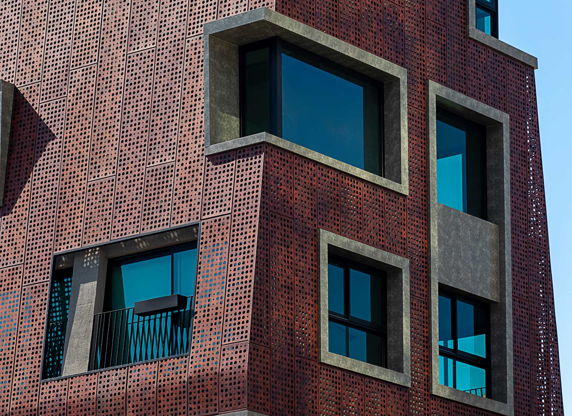 A modern building with concrete window frames and perforated metal panels.