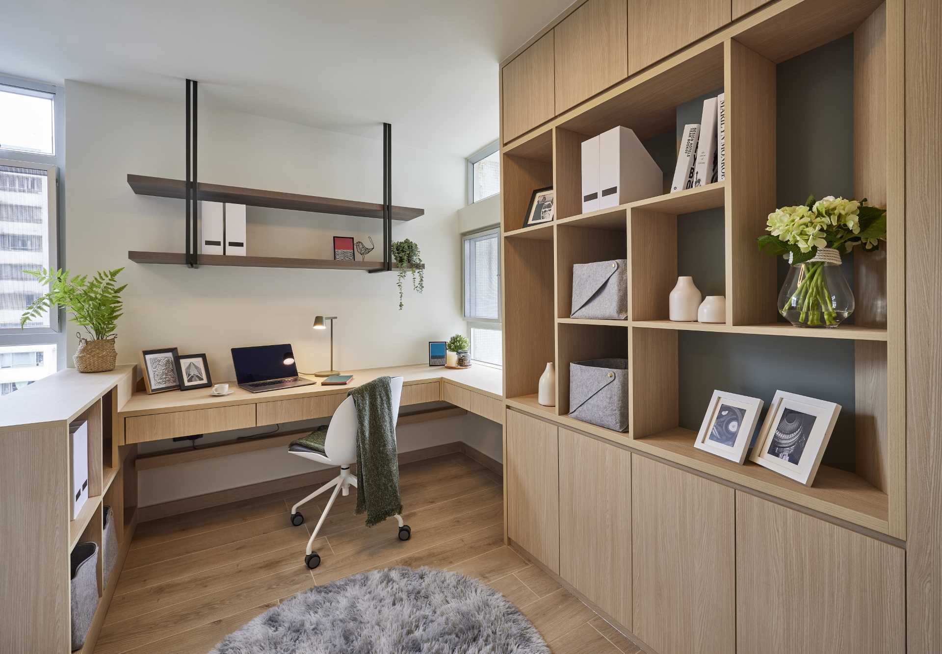This modern built-in home office includes shelving mounted above the desk, a low cabinet on the left, and a tall cabinet with shelving on the right.
