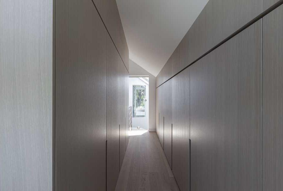 A modern closet with minimalist wood cabinets.