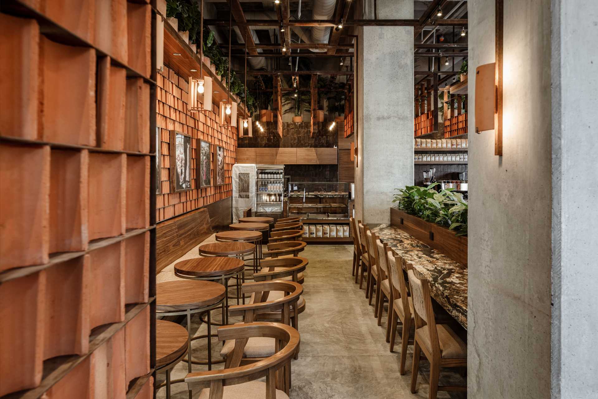 A modern coffee shop interior with plants, clay tiles, wood, and raw concrete.