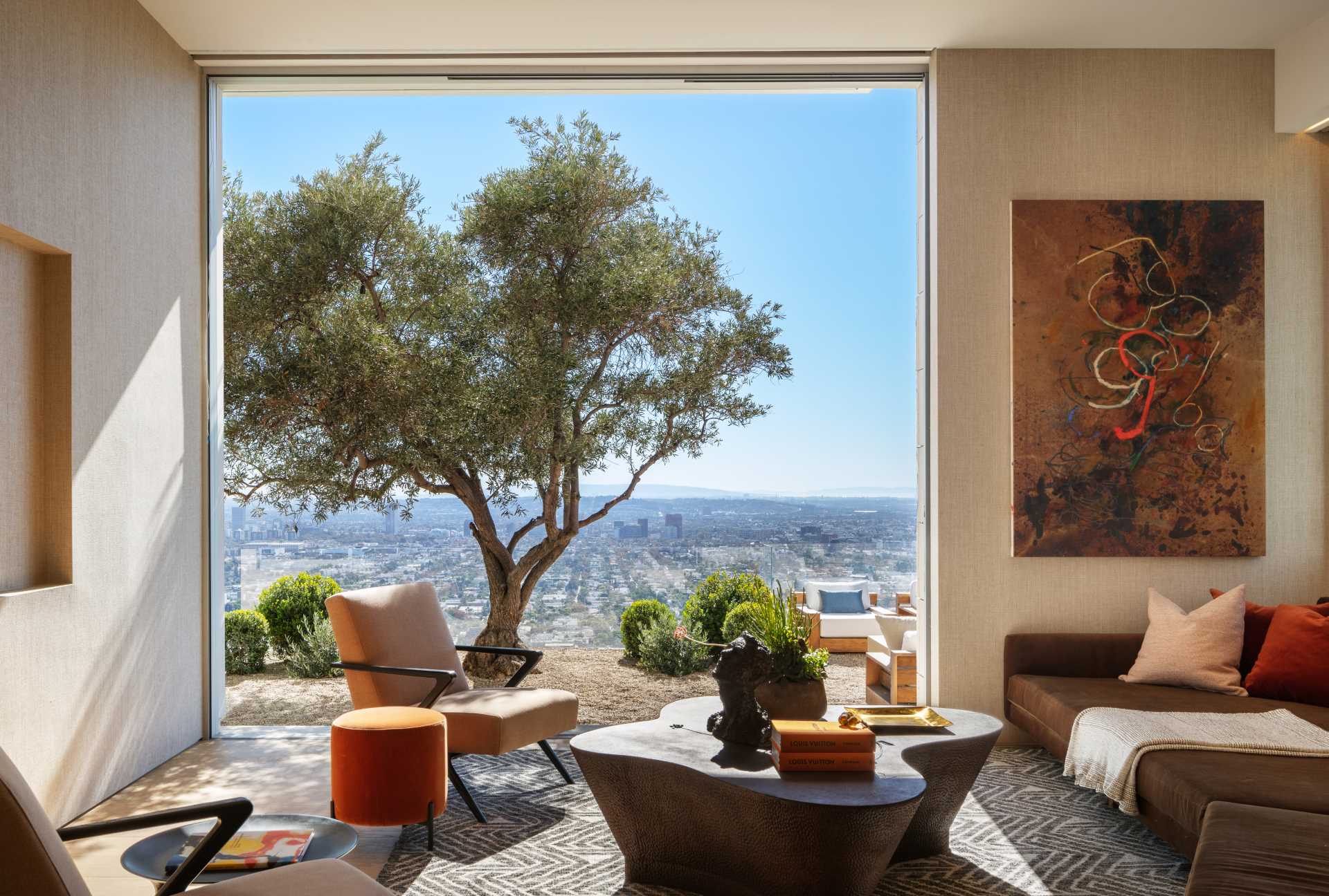 This modern living room has large windows that open to connect with the outdoors.