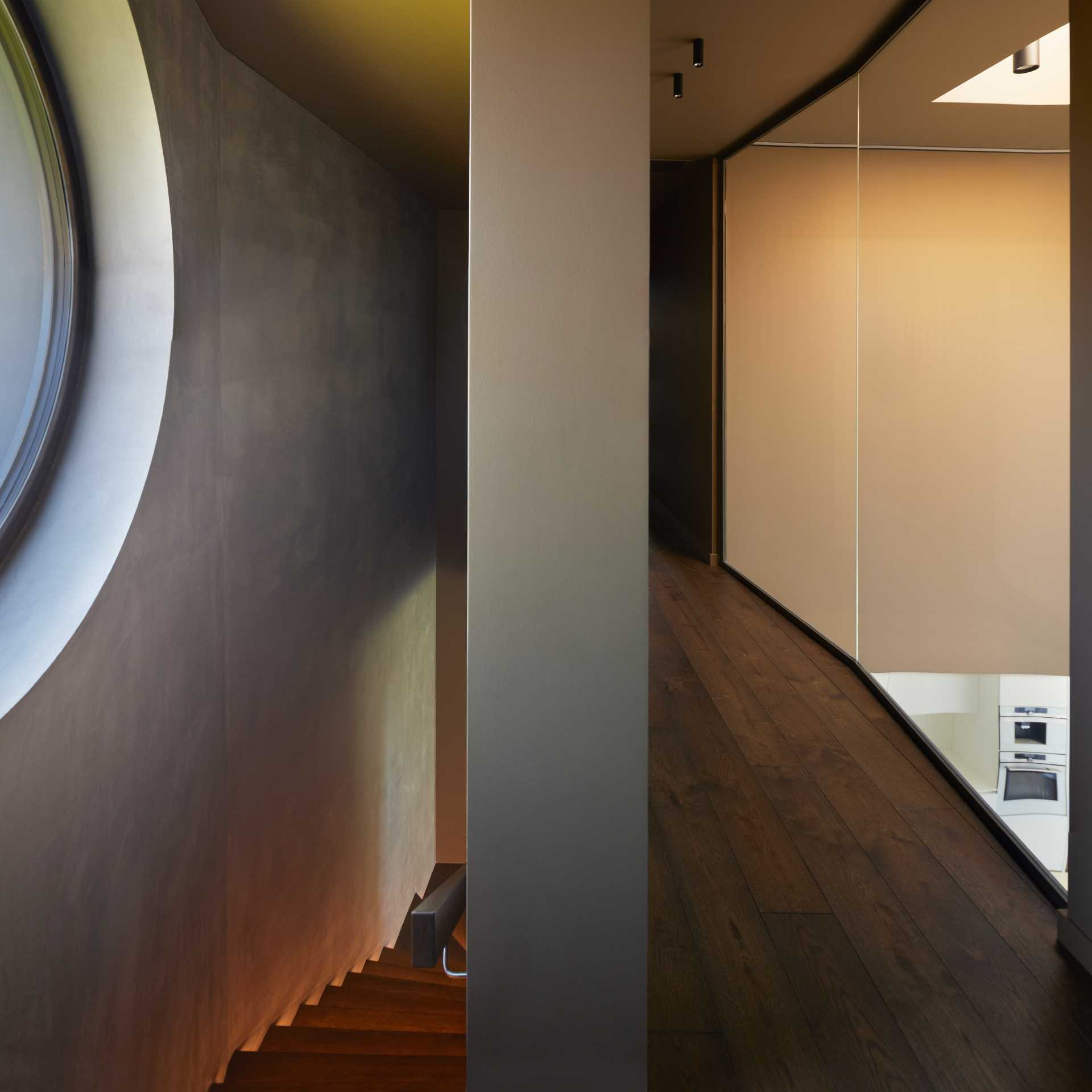 Looking down the stairs from the second level of the home, shows the glow of the lights along the wall.